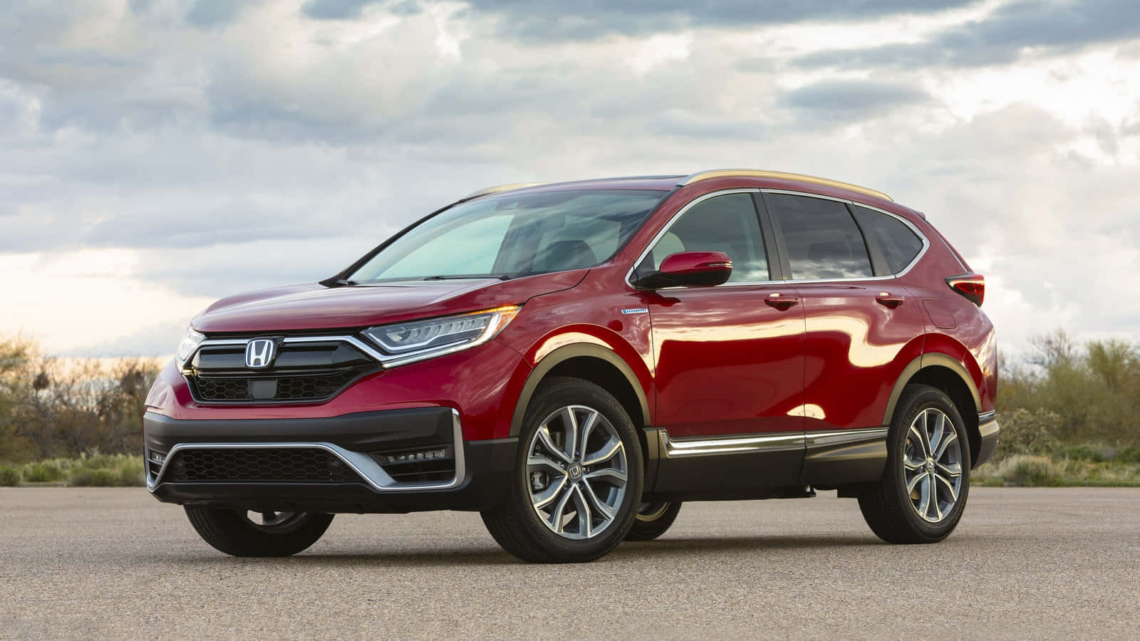 Honda Cr-v 桌布 壁紙 — 一輛亮紅色本田CR-V SUV停泊在瀝青路上，背景是陰天和沙漠灌木。