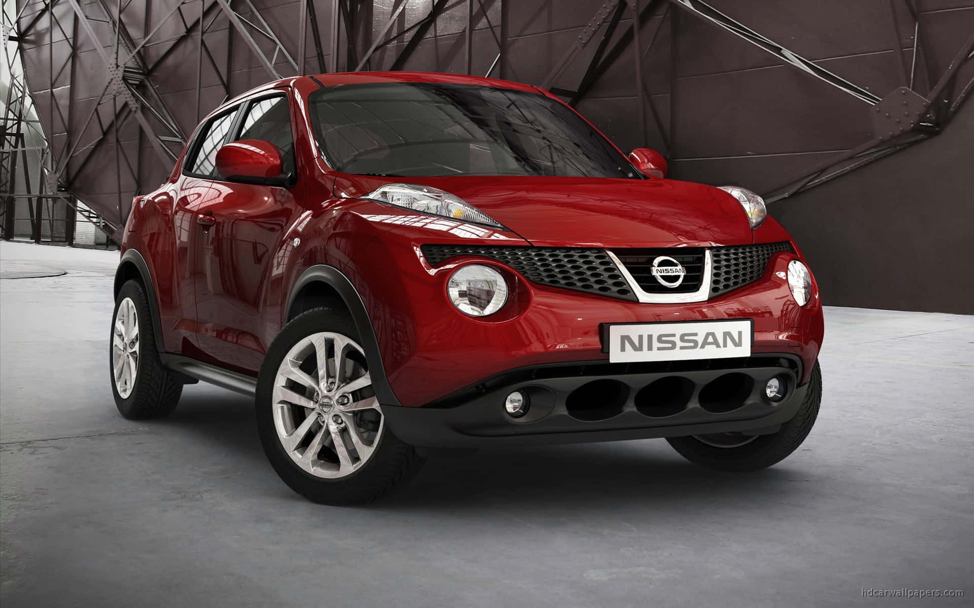 Nissan Juke 桌布 壁紙 — 一輛亮紅色的日產Juke SUV在現代工業風格的工作室中展示，工作室有幾何金屬牆壁和混凝土地板。