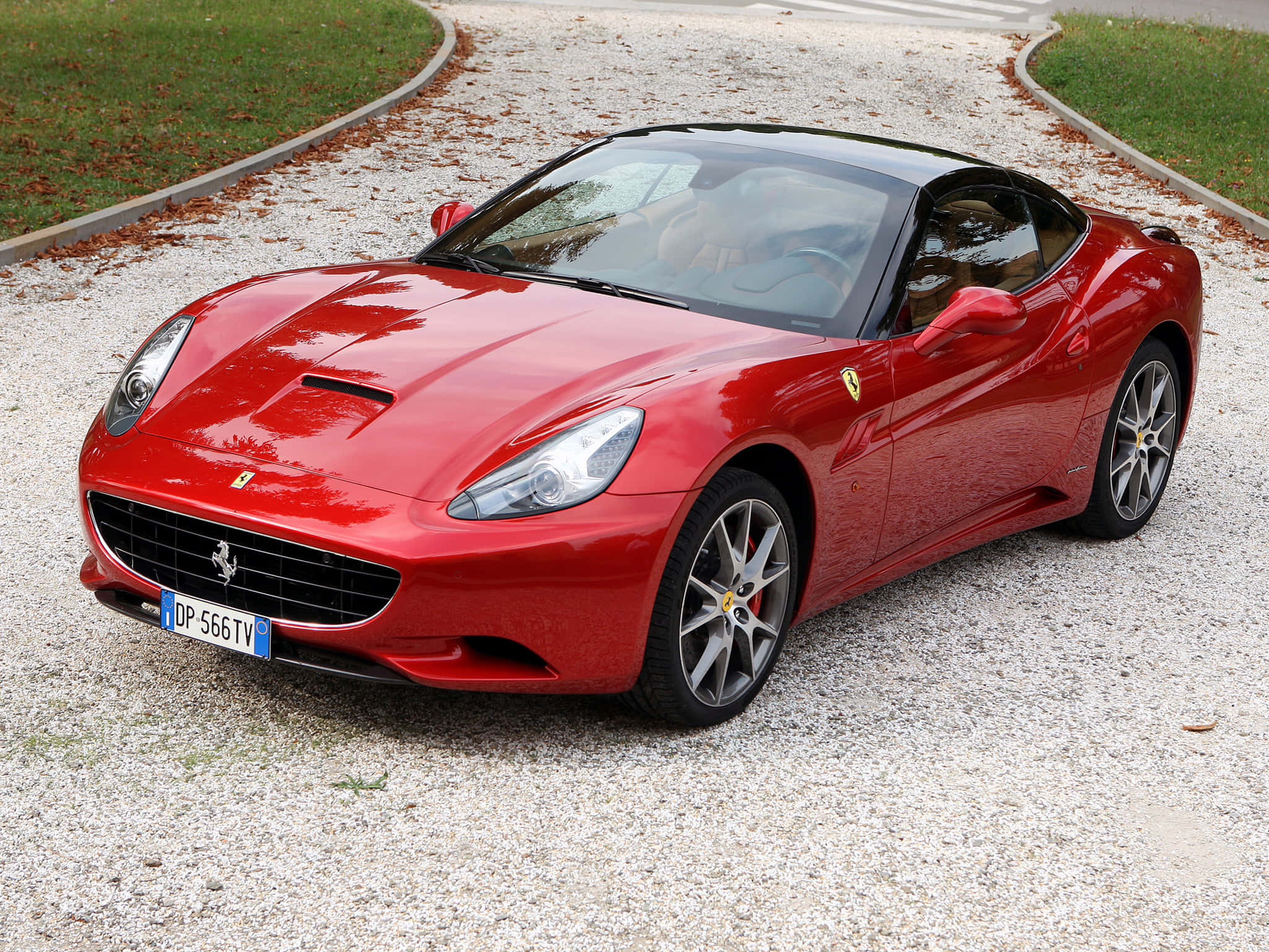 Ferrari Ff 桌布 壁紙 — 一輛亮紅色法拉利加利福尼亞跑車停放在碎石車道上，附近有草和落葉。