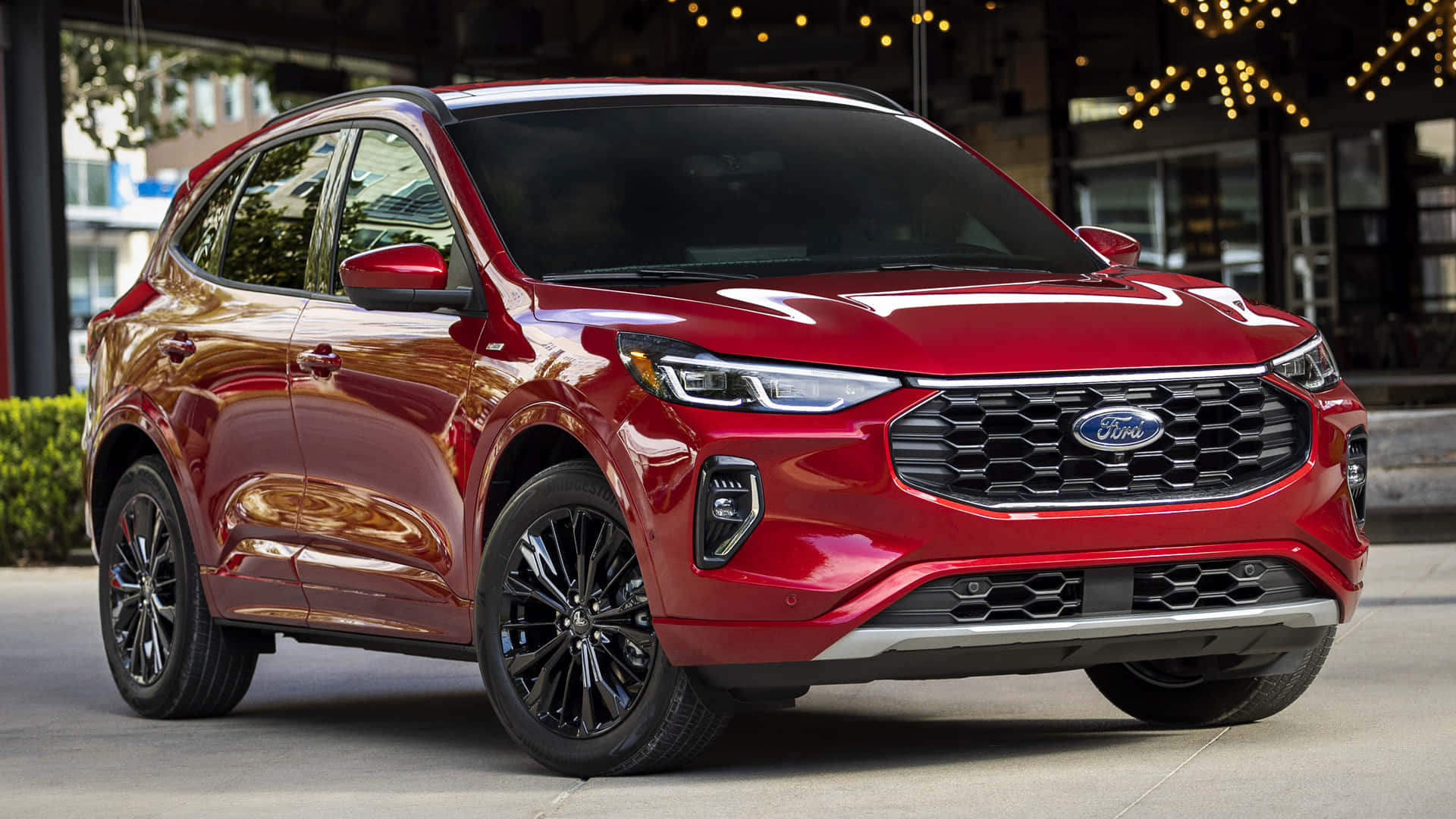 Ford Escape 桌布 壁紙 — 一輛亮紅色福特SUV停在城市人行道上，上方有燈串，背景為現代建築。
