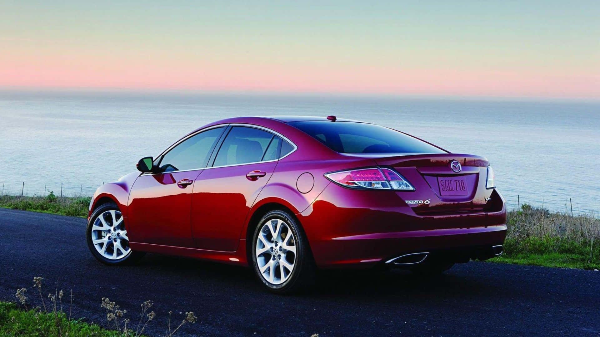 Mazda 6 桌布 壁紙 — 一輛亮紅色Mazda 6轎車停放在日落時分的海岸公路上，背後是海洋地平線。