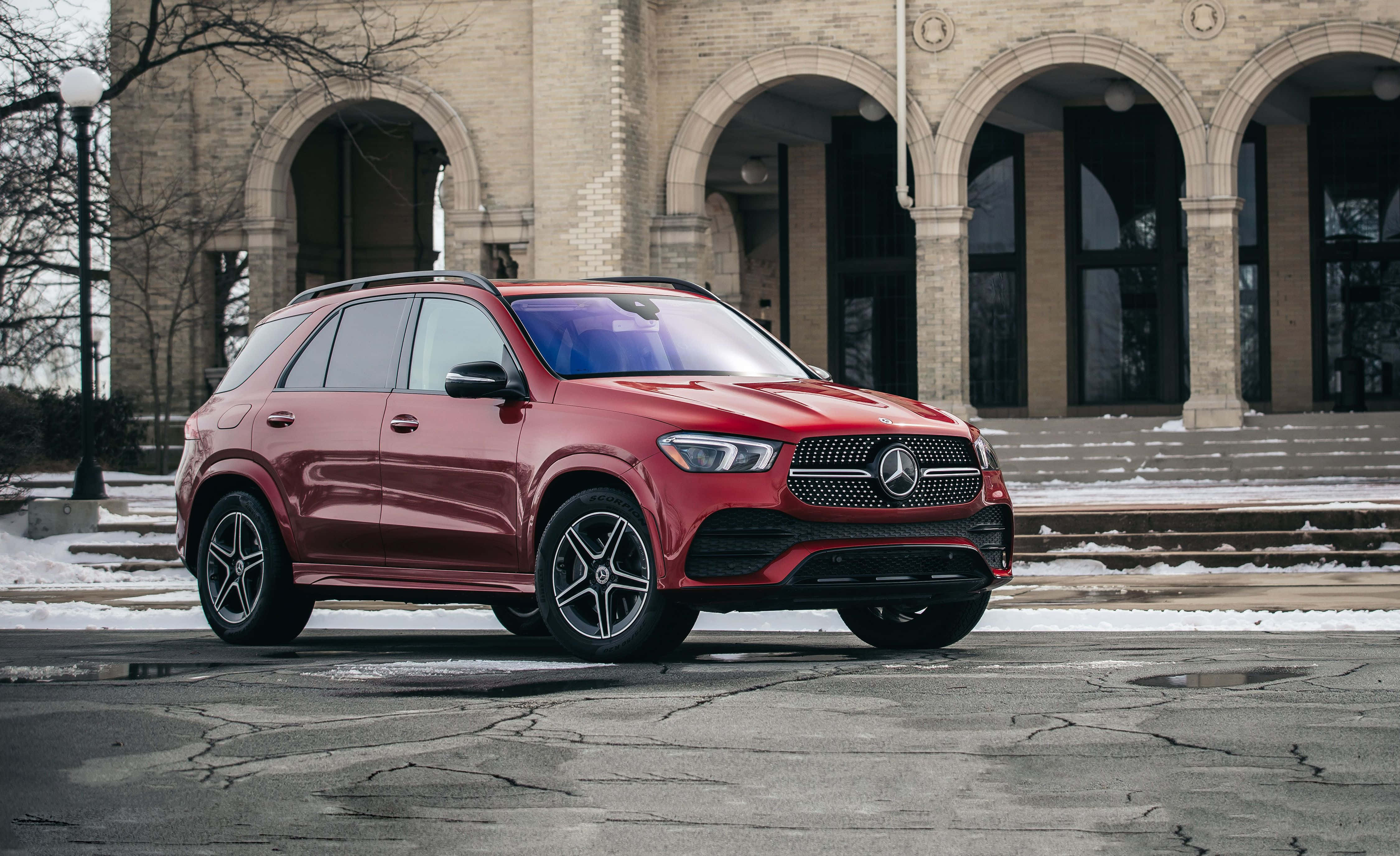 Mercedes Benz Gle-class 桌布 壁紙 — 一輛亮紅色Mercedes-Benz SUV停泊在雪地人行道上，前方是一座有拱形入口的宏偉石建築。