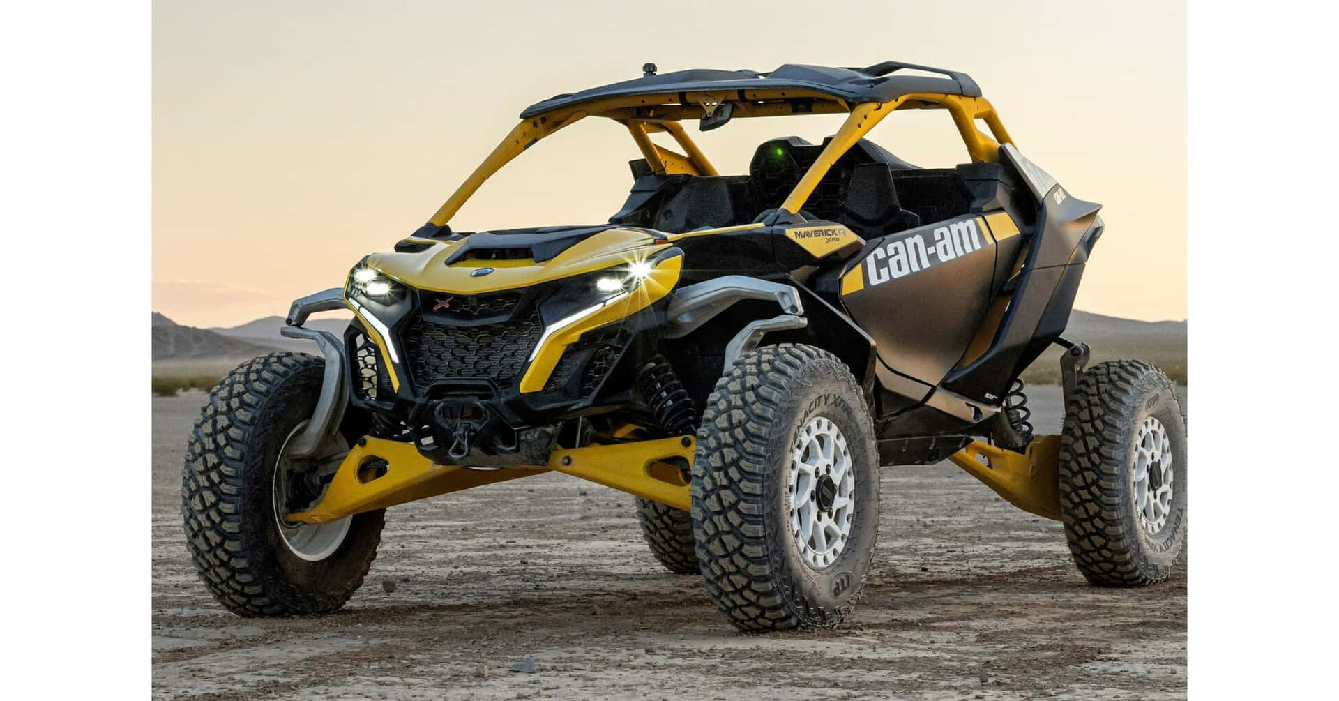  壁紙 — 一輛黃色和黑色的Can-Am Maverick X DS越野車在日落時分停在塵土飛揚的沙漠地形上。