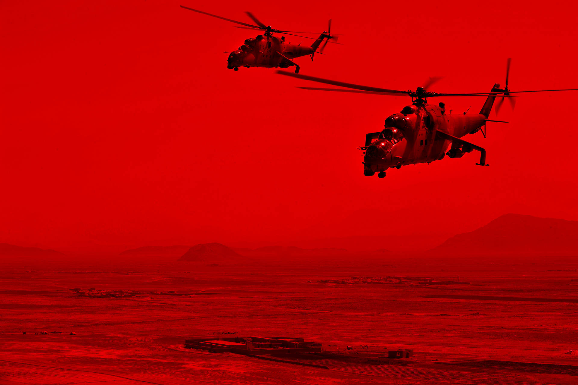 兩架軍用直升機在黃昏時分飛越紅色沙漠。 — 4K 壁紙