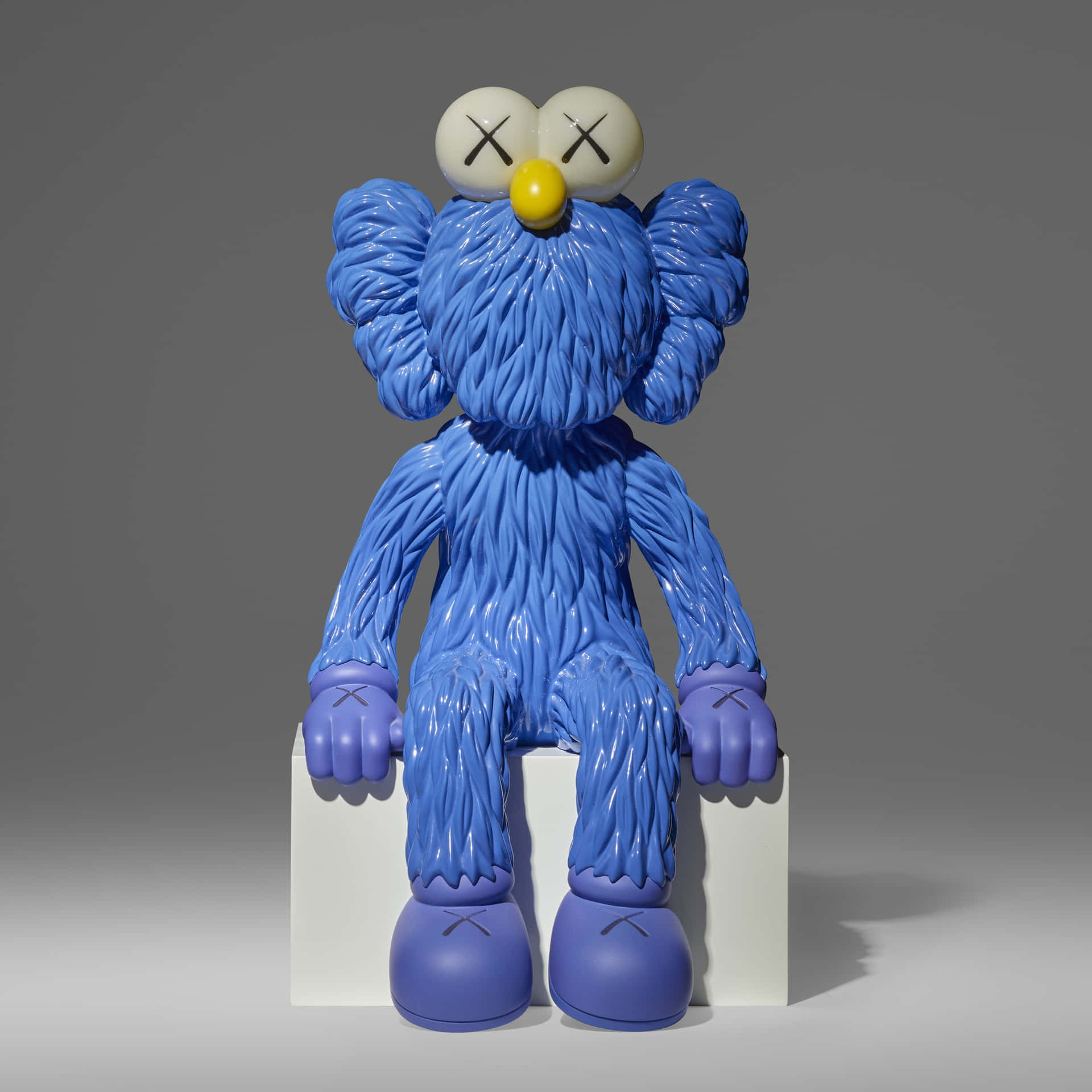  壁紙 — 一尊帶有X形眼睛的亮藍色KAWS Companion雕塑，靜靜地坐在白色底座上，背景是中性灰色攝影棚。