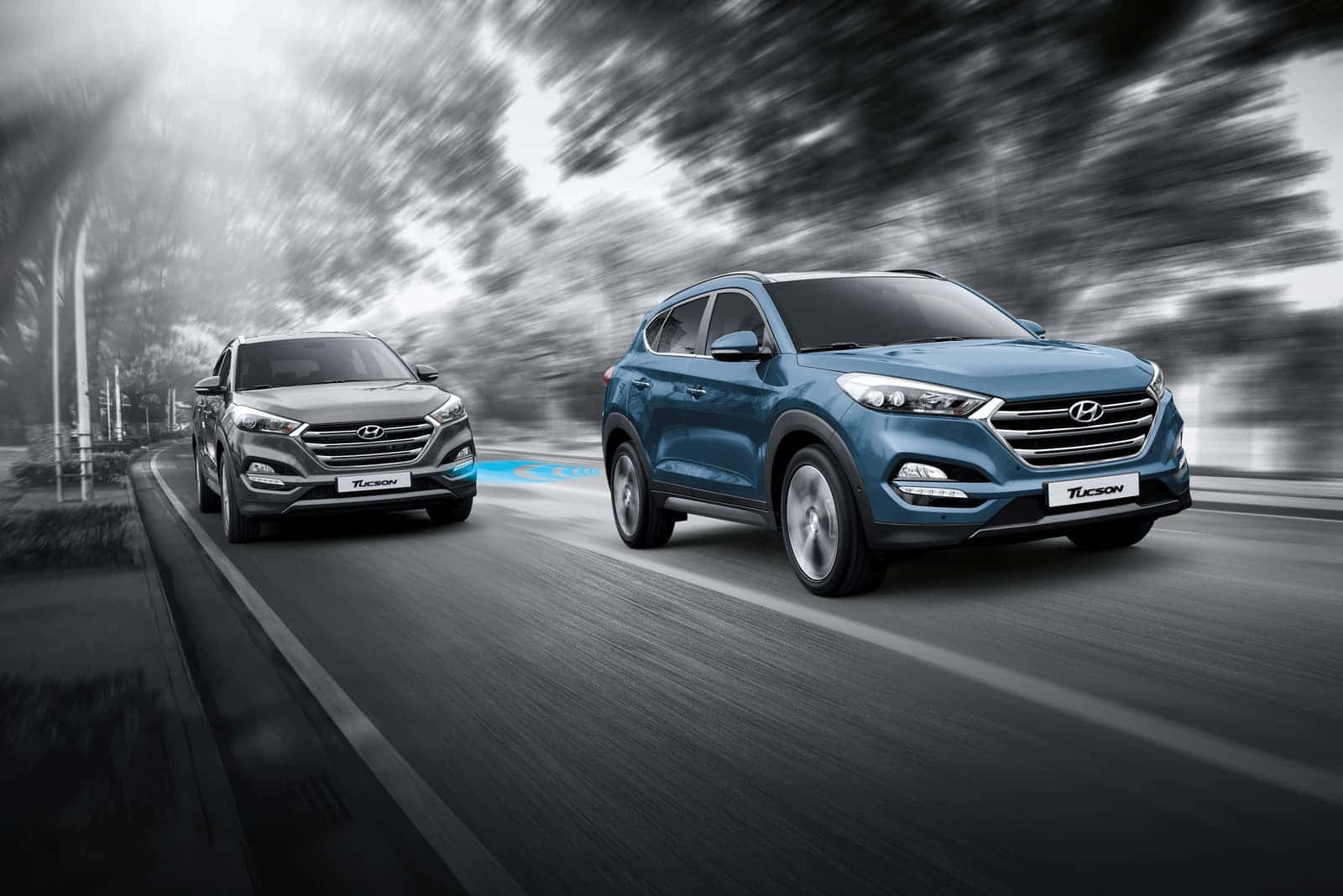 Hyundai Tucson 桌布 壁紙 — 兩輛現代Tucson SUV在單色背景的模糊道路上並排行駛，帶有運動條紋。