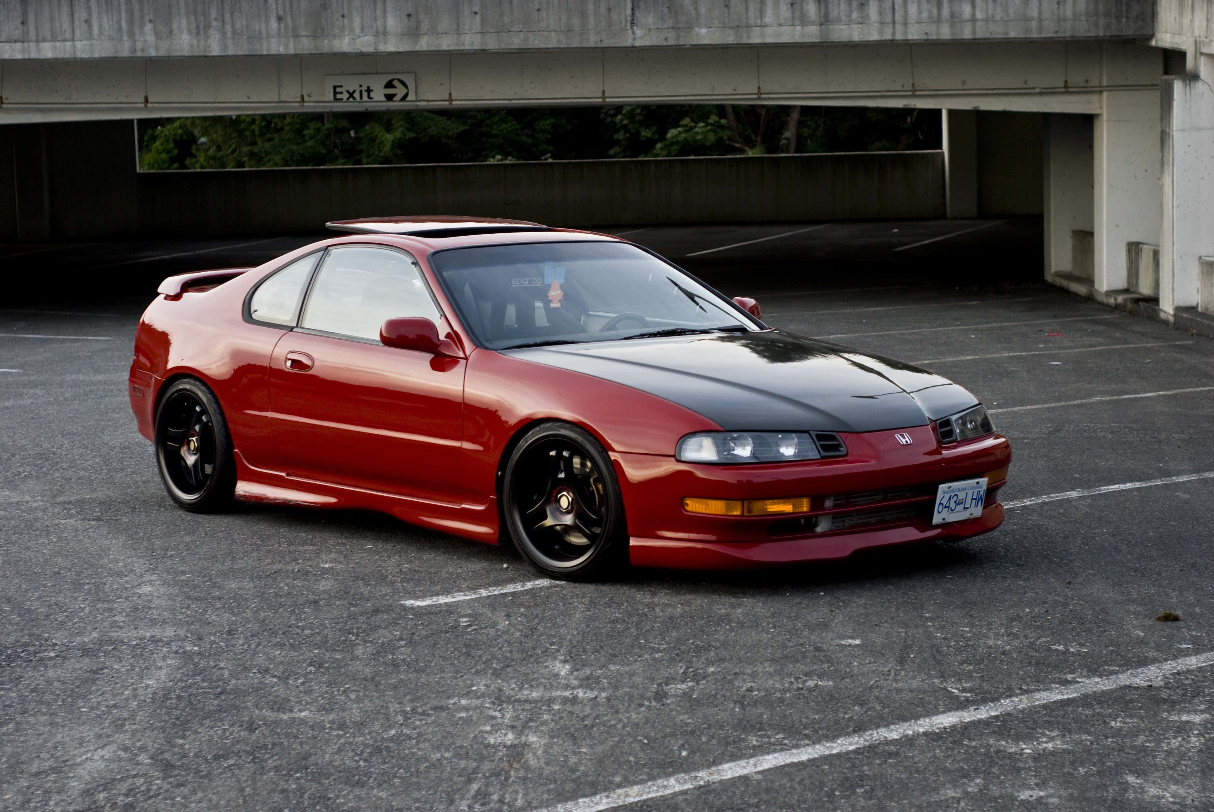 Honda Prelude 桌布 壁紙 — 一輛亮面紅黑色跑車停放在混凝土高架橋下，背景可見綠植。