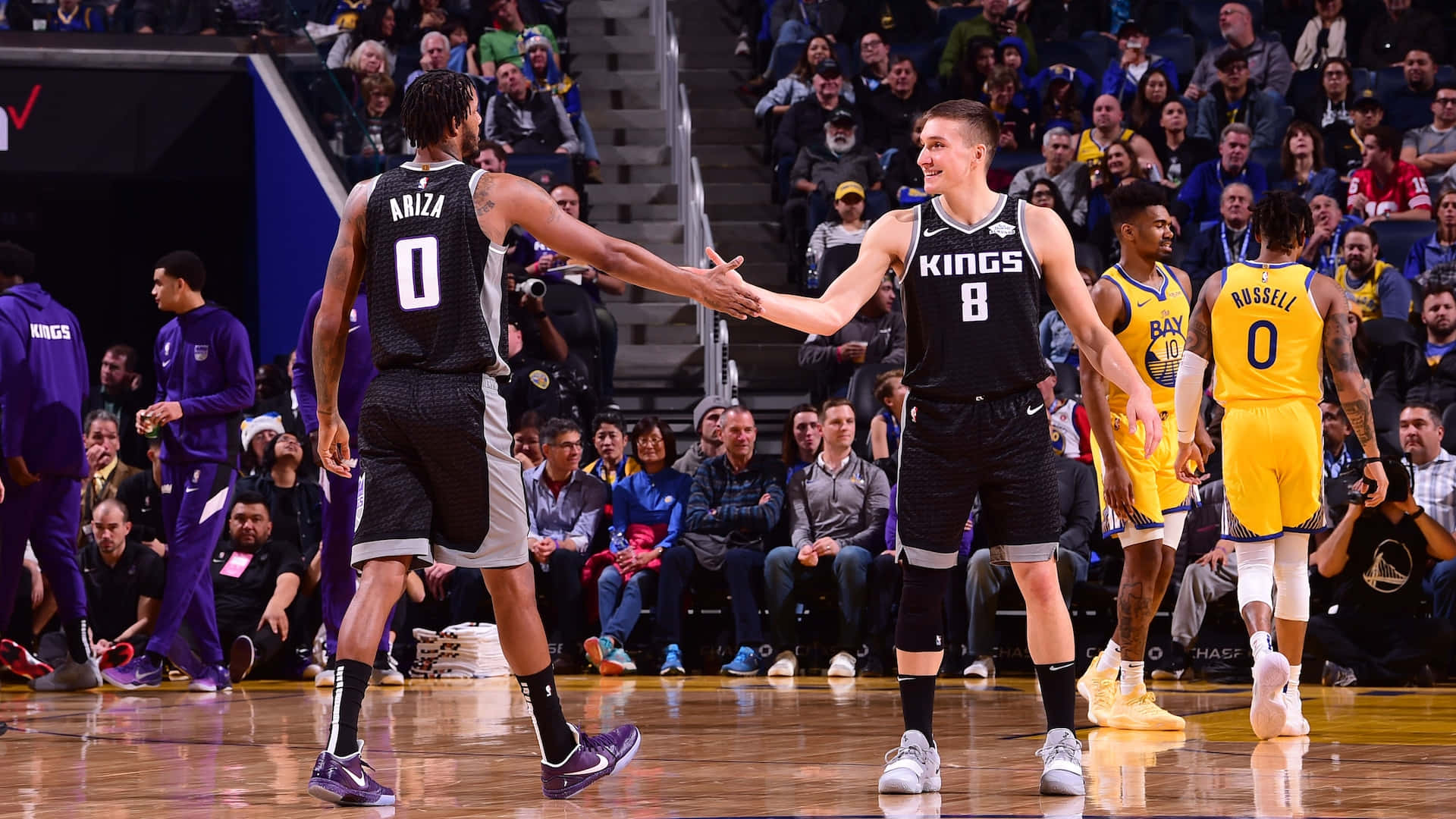 兩名籃球運動員在比賽中握手，身後有觀眾。 — NBA 壁紙