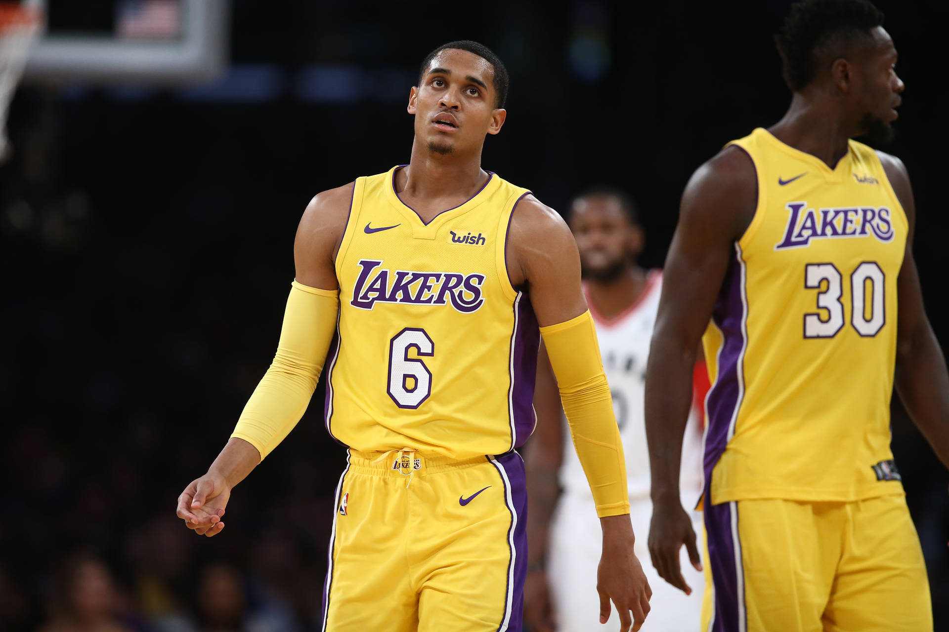 兩名身穿黃色和紫色球衣的湖人籃球運動員在比賽中的球場上。 — NBA 壁紙