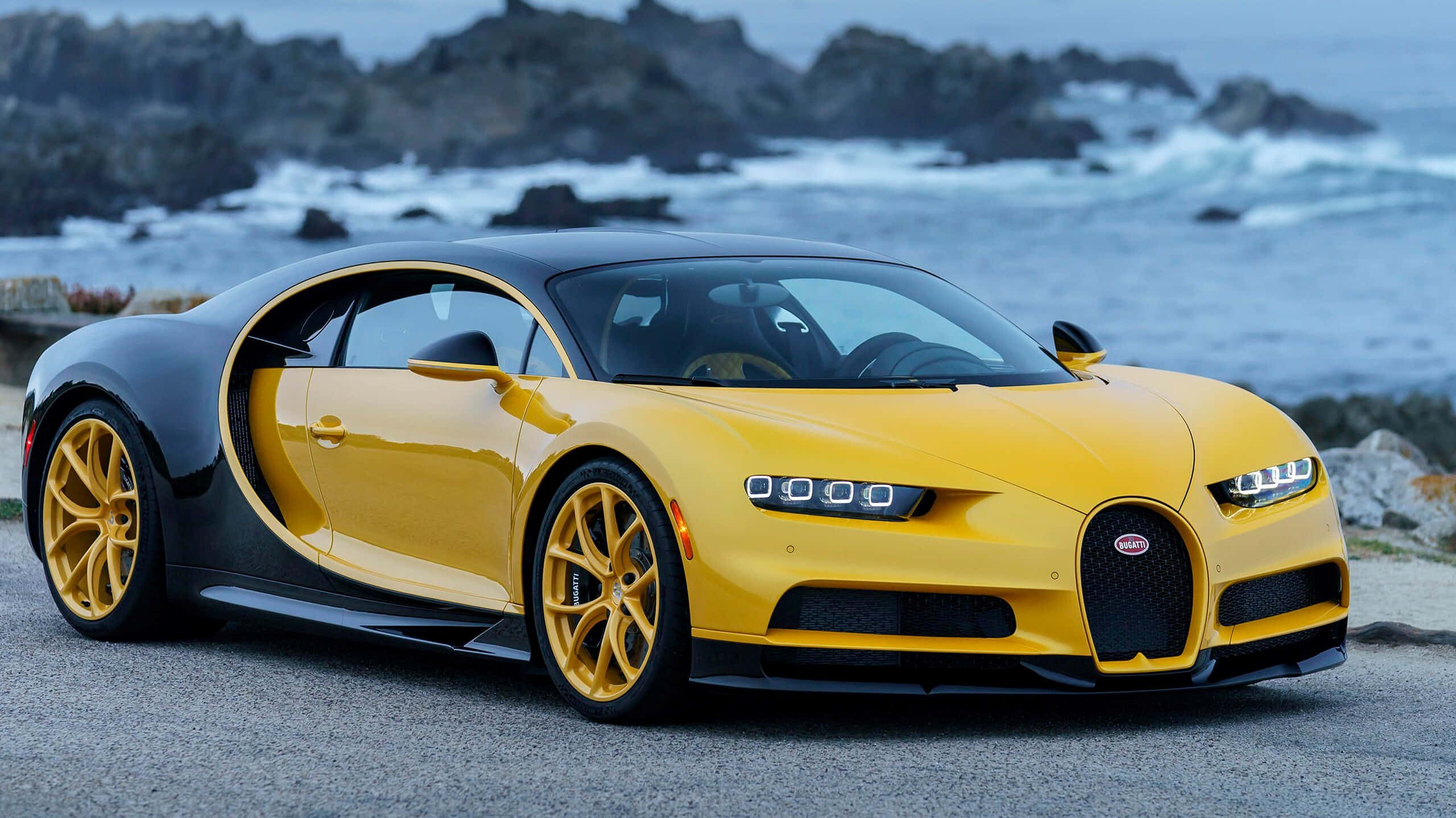 Bugatti Chiron 桌布 壁紙 — 一輛搶眼的黃黑配色布加迪Chiron停泊在海岸公路上，背後有翻騰的海浪。
