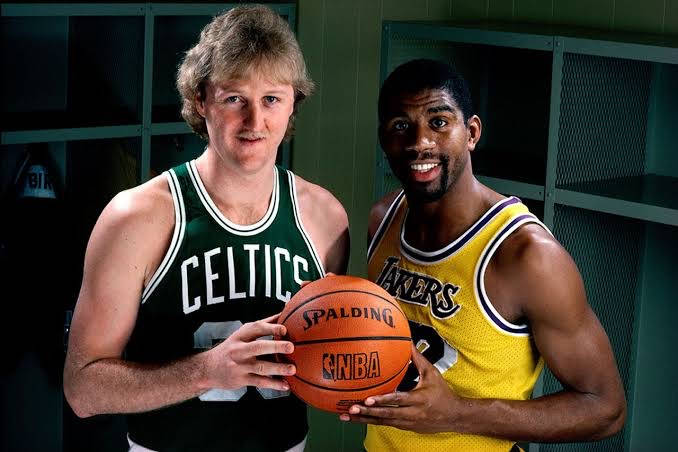 兩位身穿復古球衣的NBA籃球運動員在更衣室裡拿著一個籃球。 — NBA 壁紙