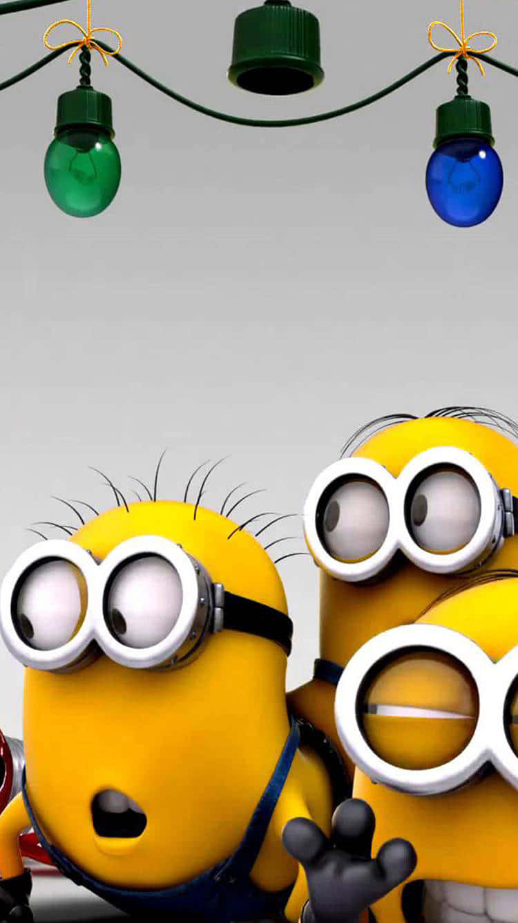  壁紙 — 兩隻黃色的Minions戴著護目鏡在色彩繽紛的燈串下方向上看，背景是純灰色。