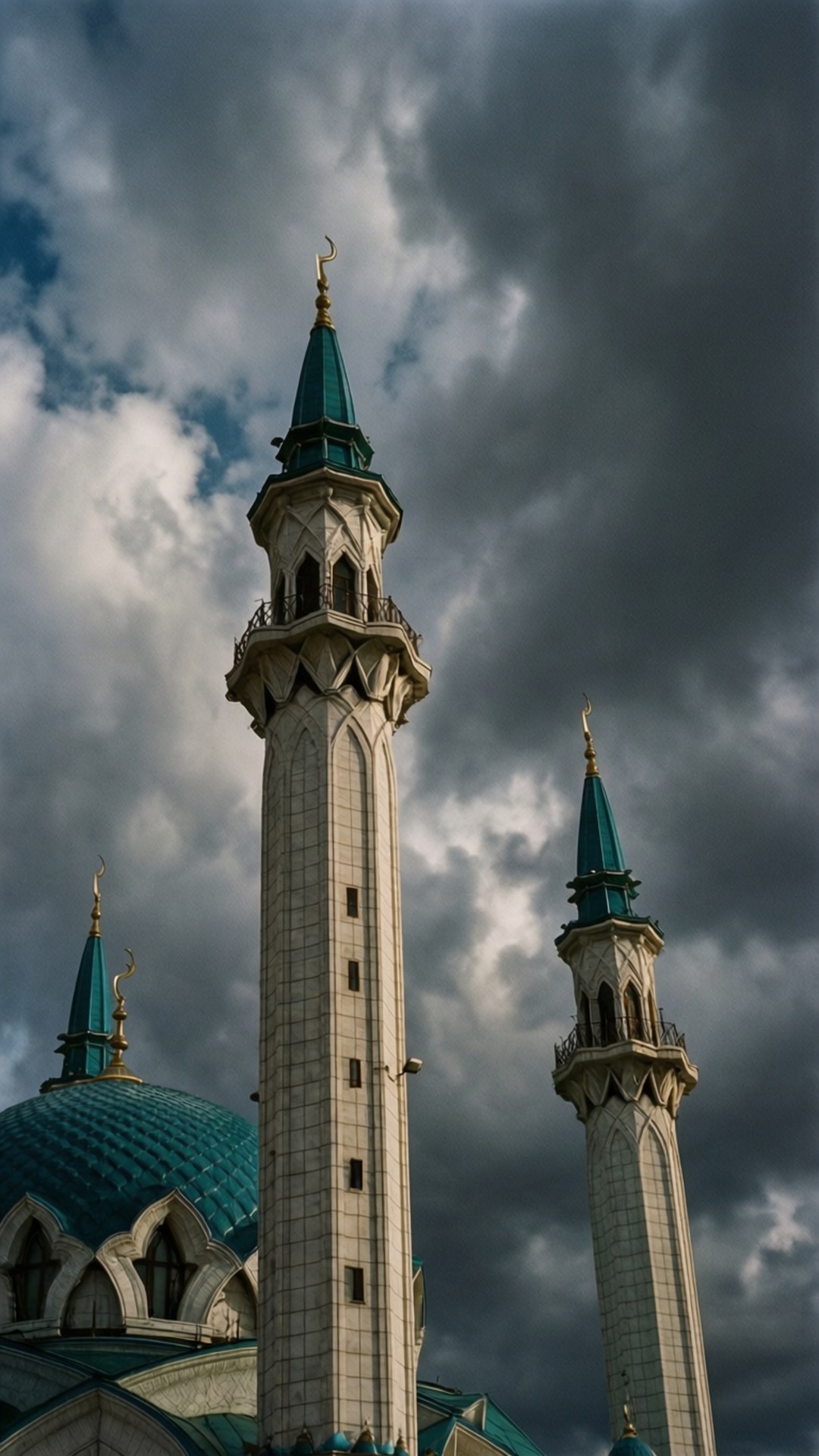 Mosque Minarets Dramatic Sky 壁紙 — 兩座高大的白色宣禮塔，帶有藍綠色圓頂和新月形頂部，在戲劇性的多雲天空下聳立。