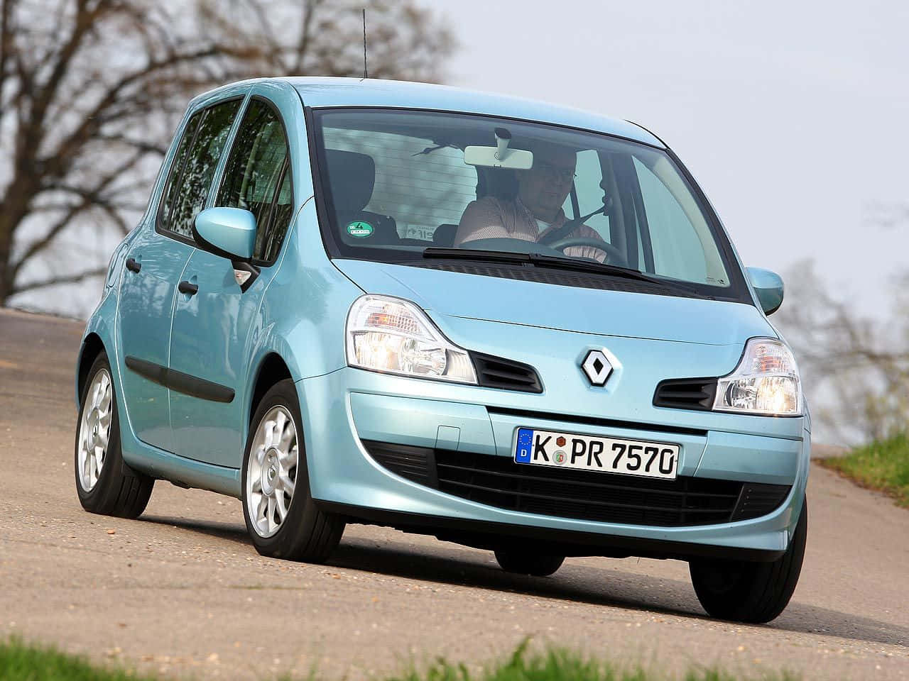 Renault Modus 桌布 壁紙 — 一輛淺藍色的雷諾Kaptur在鄉村道路上行駛，背景是光禿禿的樹木和多雲的天空。