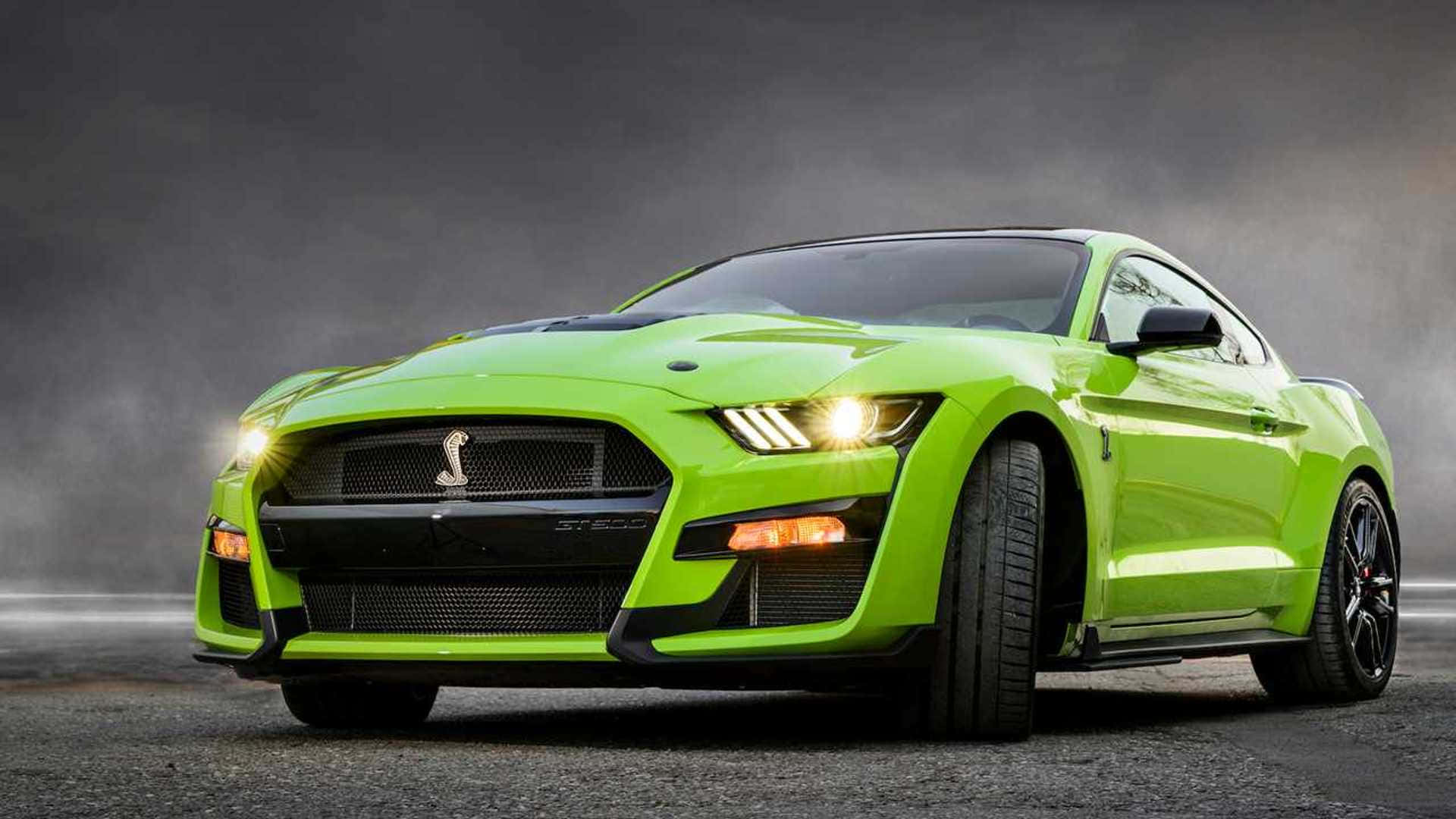  壁紙 — 一輛充滿活力的萊姆綠色福特野馬 Shelby GT500，在戲劇性燈光下，以發光的頭燈主導著霧氣瀰漫的灰色瀝青道路。
