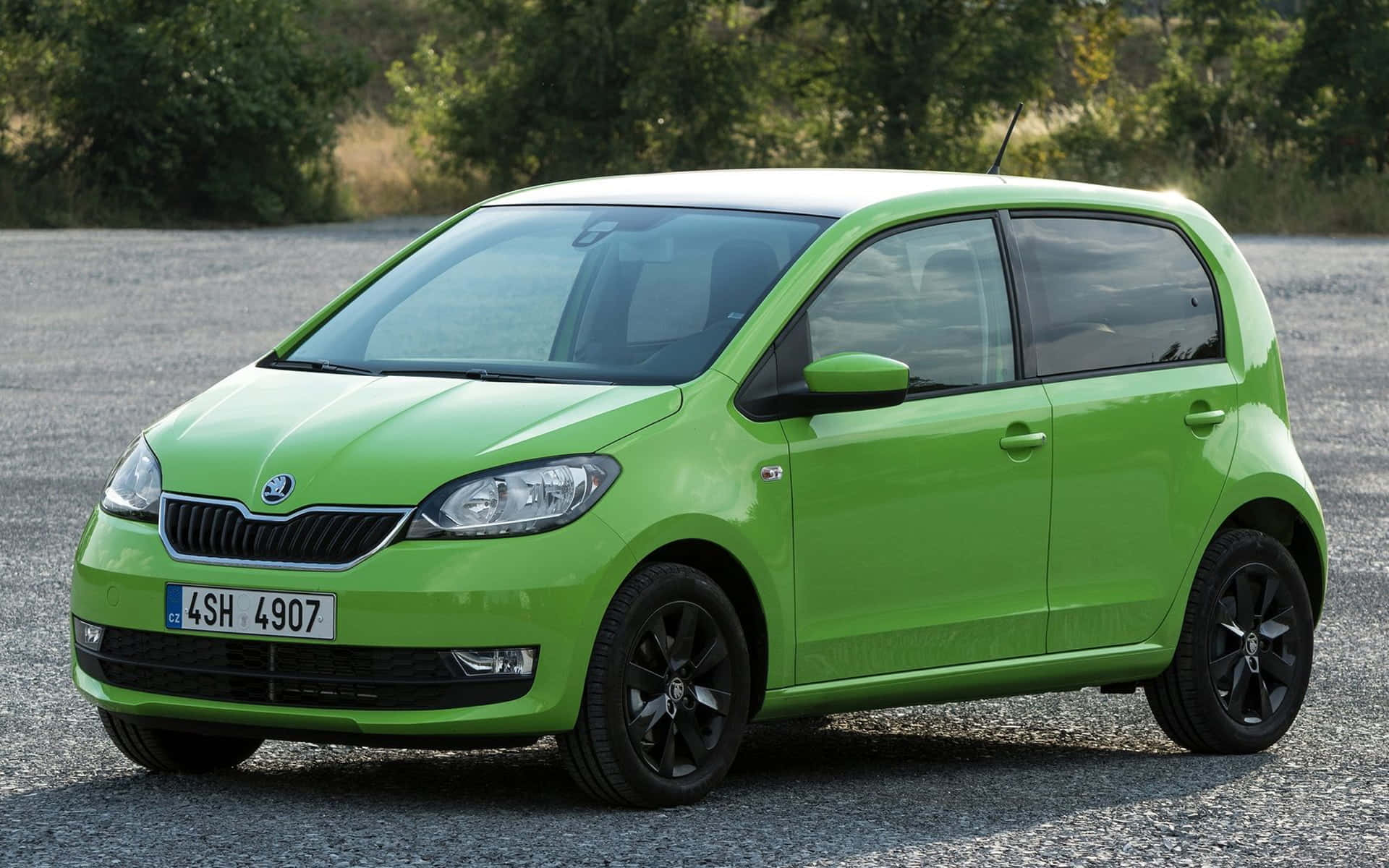Skoda Citigo 桌布 壁紙 — 一輛充滿活力的萊姆綠色Skoda掀背車停在碎石上，背景有樹木。