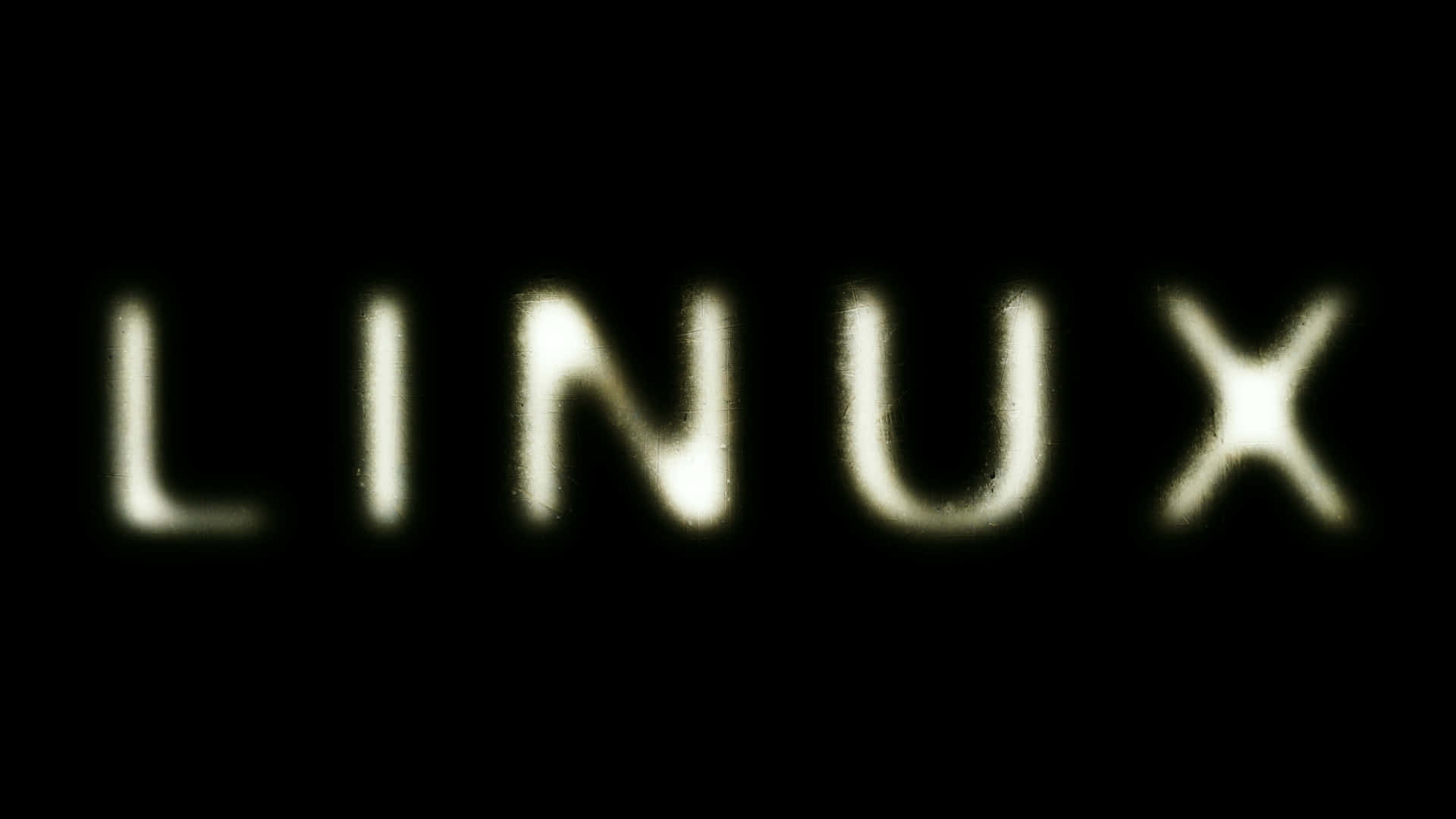 Linux 桌布 壁紙 — LINUX 這個字在深黑色背景上以淡黃色柔和發光，帶有微妙的模糊效果。