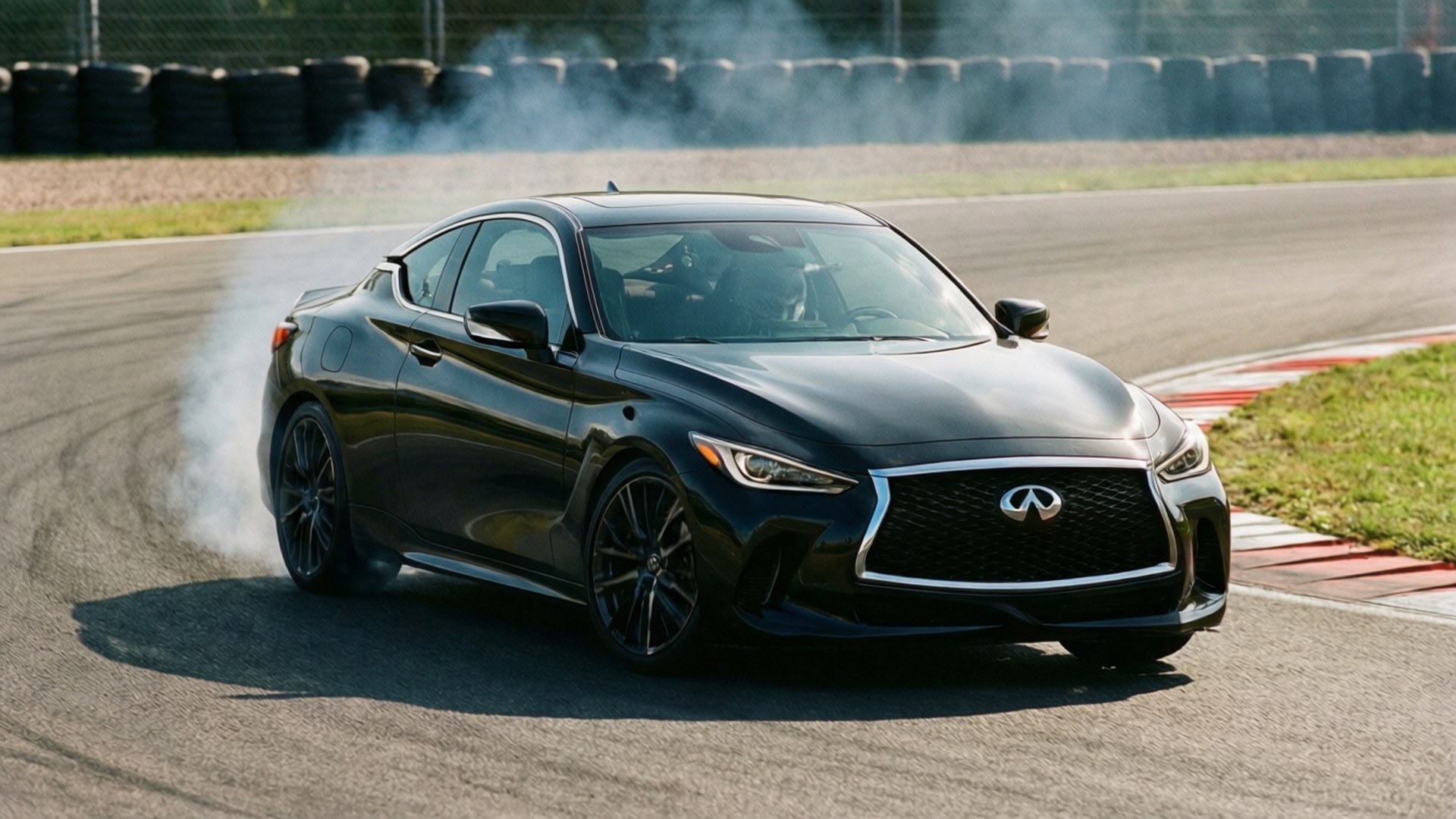 Racetrack Black S 壁紙 — 一輛流線型黑色 Infiniti 跑車在賽道彎道飄移，在明亮陽光下揚起輪胎煙霧。