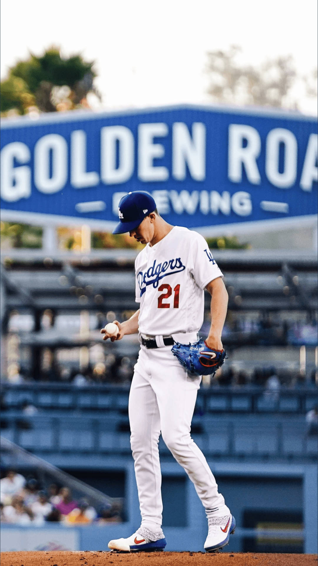 身穿道奇隊球衣的棒球運動員在球場上行走，手持球和手套。 — MLB 壁紙