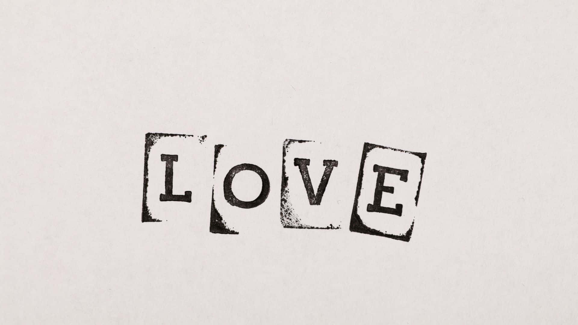 Beautiful Love 桌布 壁紙 — 「LOVE」一詞以粗體黑色墨水蓋印在帶有紋理的米白色紙張上，呈現粗糙的復古打字機效果。