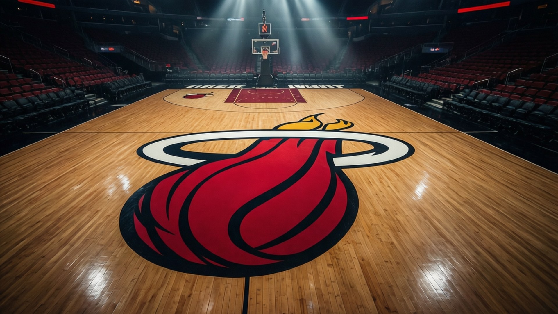 Heat Court Spotlight 壁紙 — 一個低角度視角，拍攝一個拋光木製籃球場，中央有一個大型紅色邁阿密熱火標誌，在空蕩蕩的場館中，明亮的聚光燈照射下。