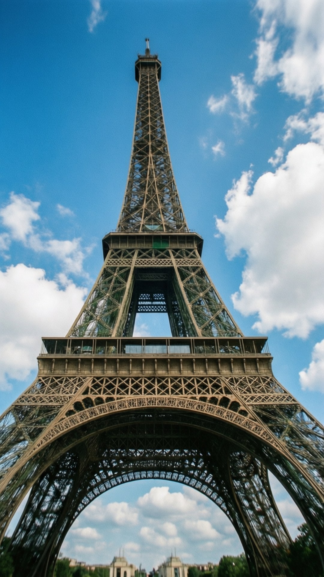 Looking Up at Eiffel 壁紙 — 從低角度觀看艾菲爾鐵塔複雜的鐵格架，在藍天白雲中高聳入雲。