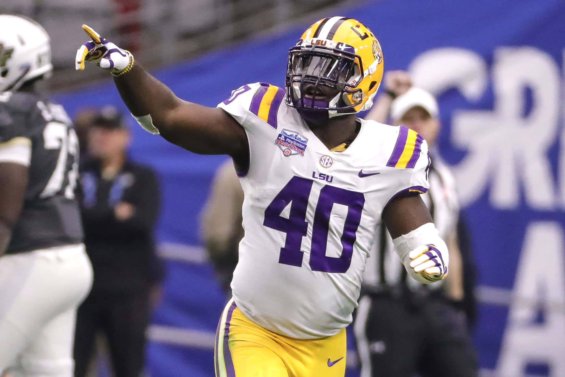 壁紙 — LSU 美式足球員 40 號身穿白色、紫色和金色球衣，在比賽中舉臂慶祝。