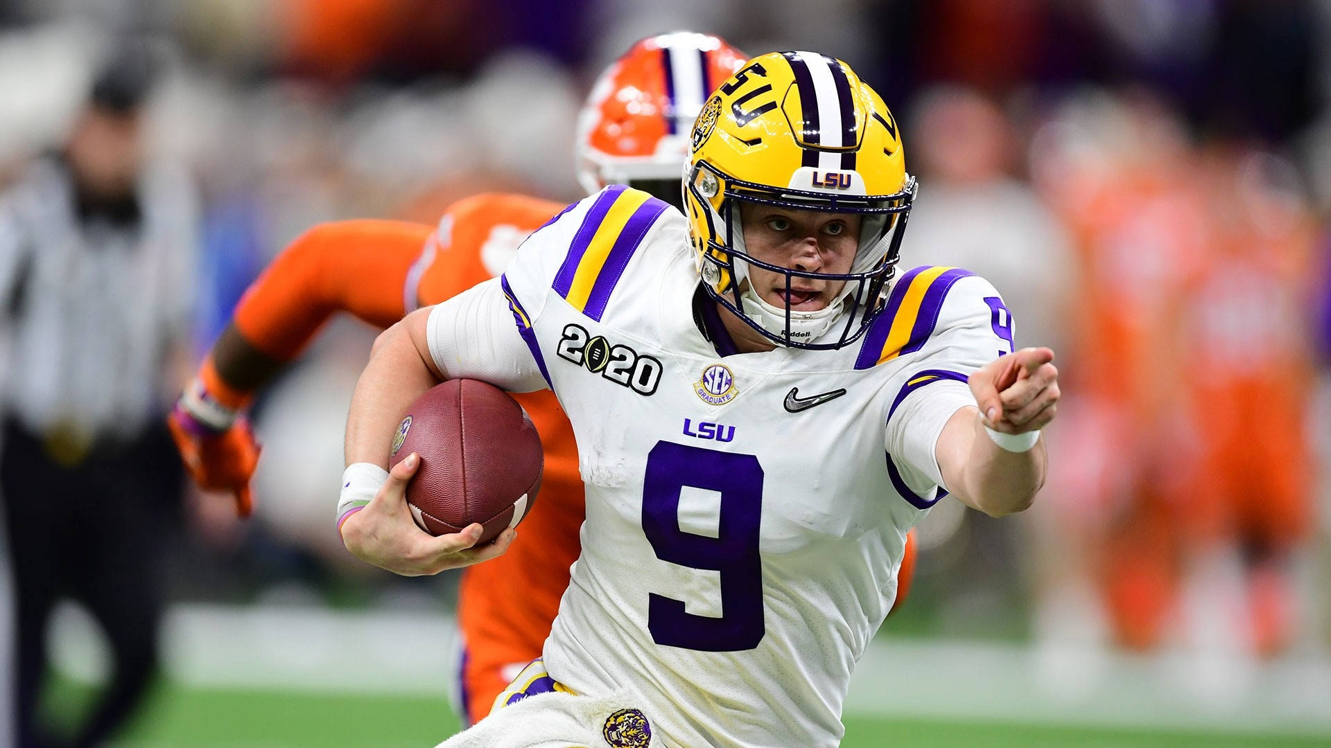 Joe Burrow 桌布 壁紙 — LSU 美式足球四分衛9號身穿白色、紫色和金色球衣在比賽中帶球奔跑。