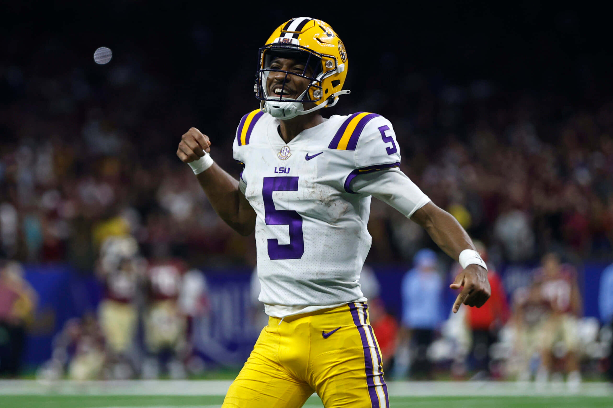 Lsu Football 桌布 壁紙 — LSU 足球四分衛 5 號身穿白色和金色球衣在體育場燈光下慶祝一次進攻。