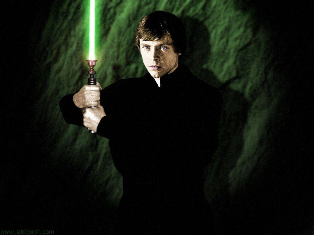 星際大戰 桌布 壁紙 — Luke Skywalker 在一個光線昏暗、帶有紋理綠色牆壁的洞穴中手持發光的綠色光劍，投射出戲劇性的陰影。