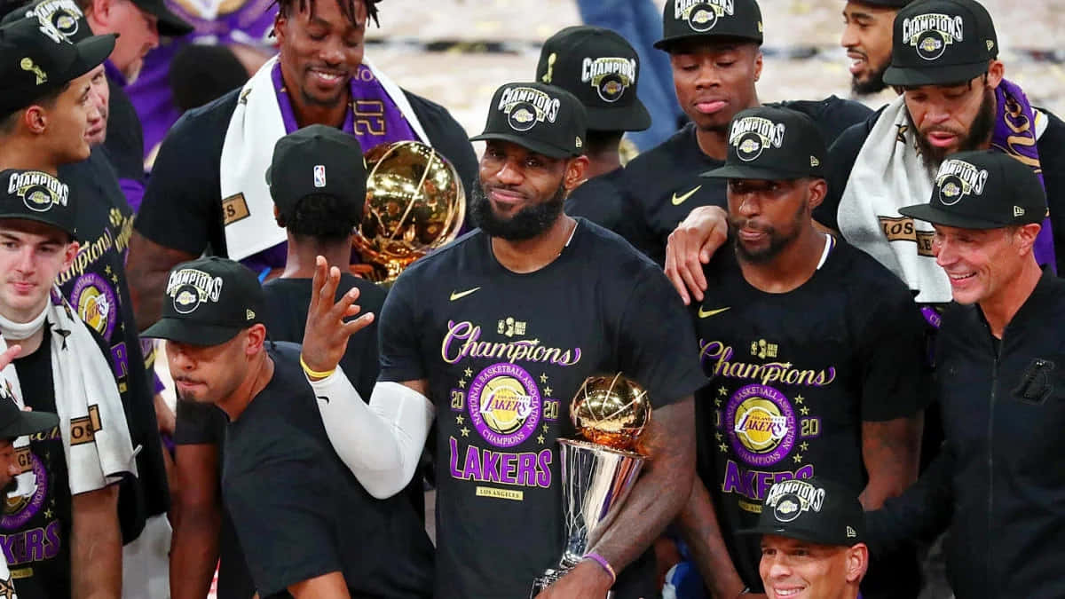  壁紙 — 洛杉磯湖人籃球隊穿著黑色「Champions」T恤和帽子，高舉獎盃慶祝冠軍勝利。