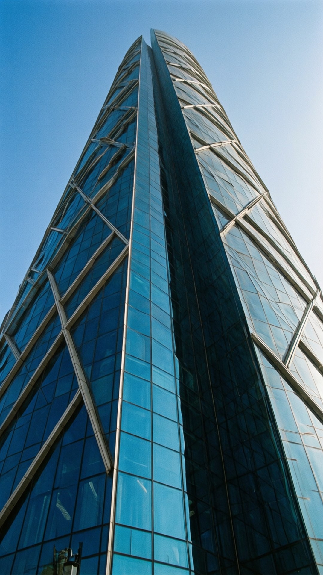 Al Hamra Tower Detail 壁紙 — 一座螺旋設計的玻璃摩天大樓在清澈的藍天下高聳入雲。