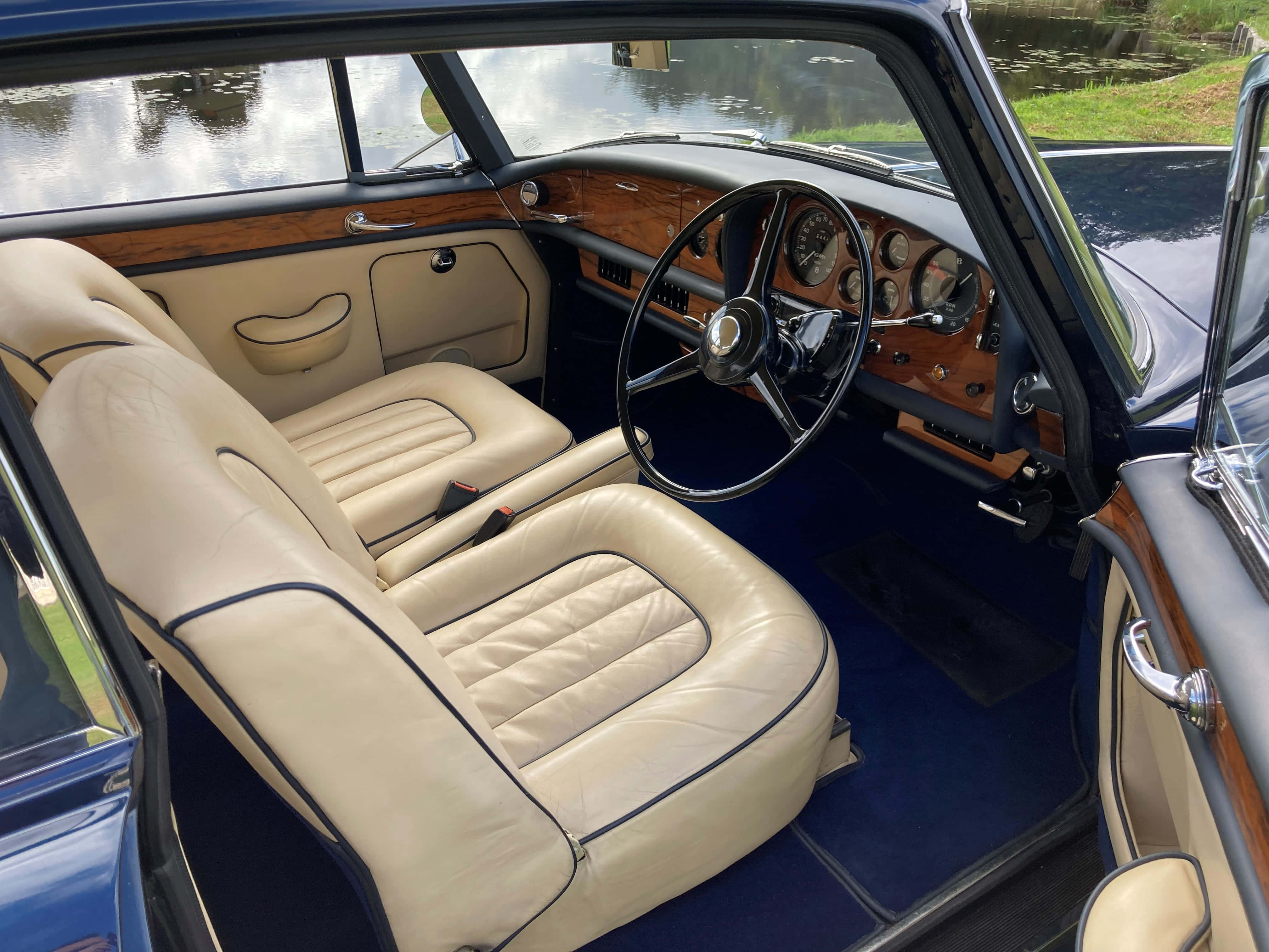 Bentley S3 桌布 壁紙 — 豪華復古車內裝，配奶油色皮革座椅和木質飾邊，俯瞰寧靜的池塘。