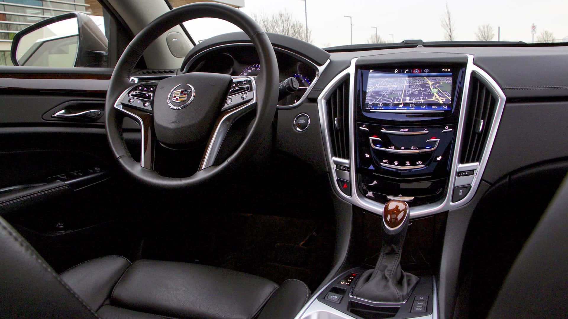 Cadillac Srx 桌布 壁紙 — 豪華車內裝，配有黑色皮革座椅和顯示地圖的數位導航螢幕。