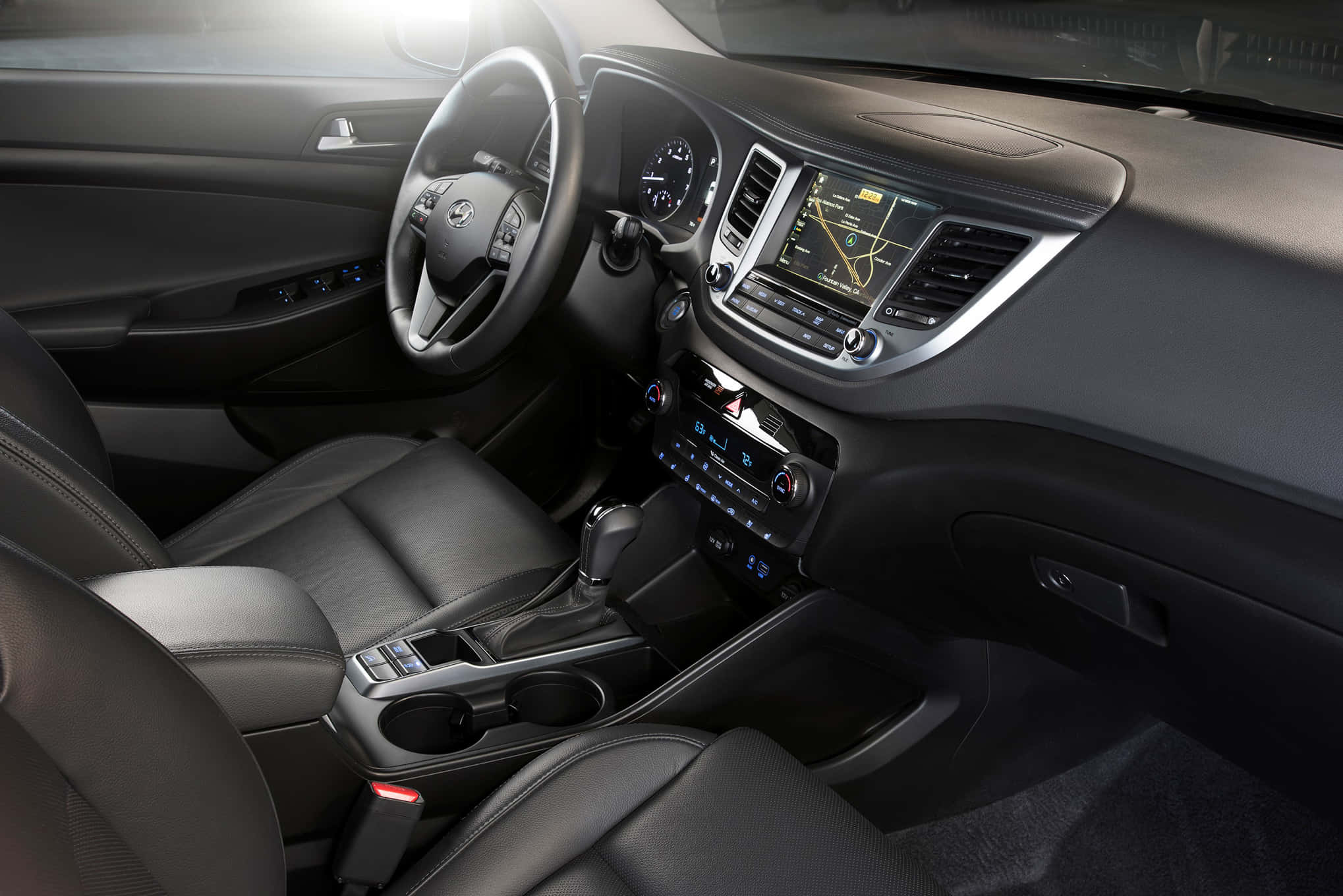 Hyundai Tucson 桌布 壁紙 — 豪華車內裝，配有黑色皮革座椅和時尚儀表板，由環境照明照亮。