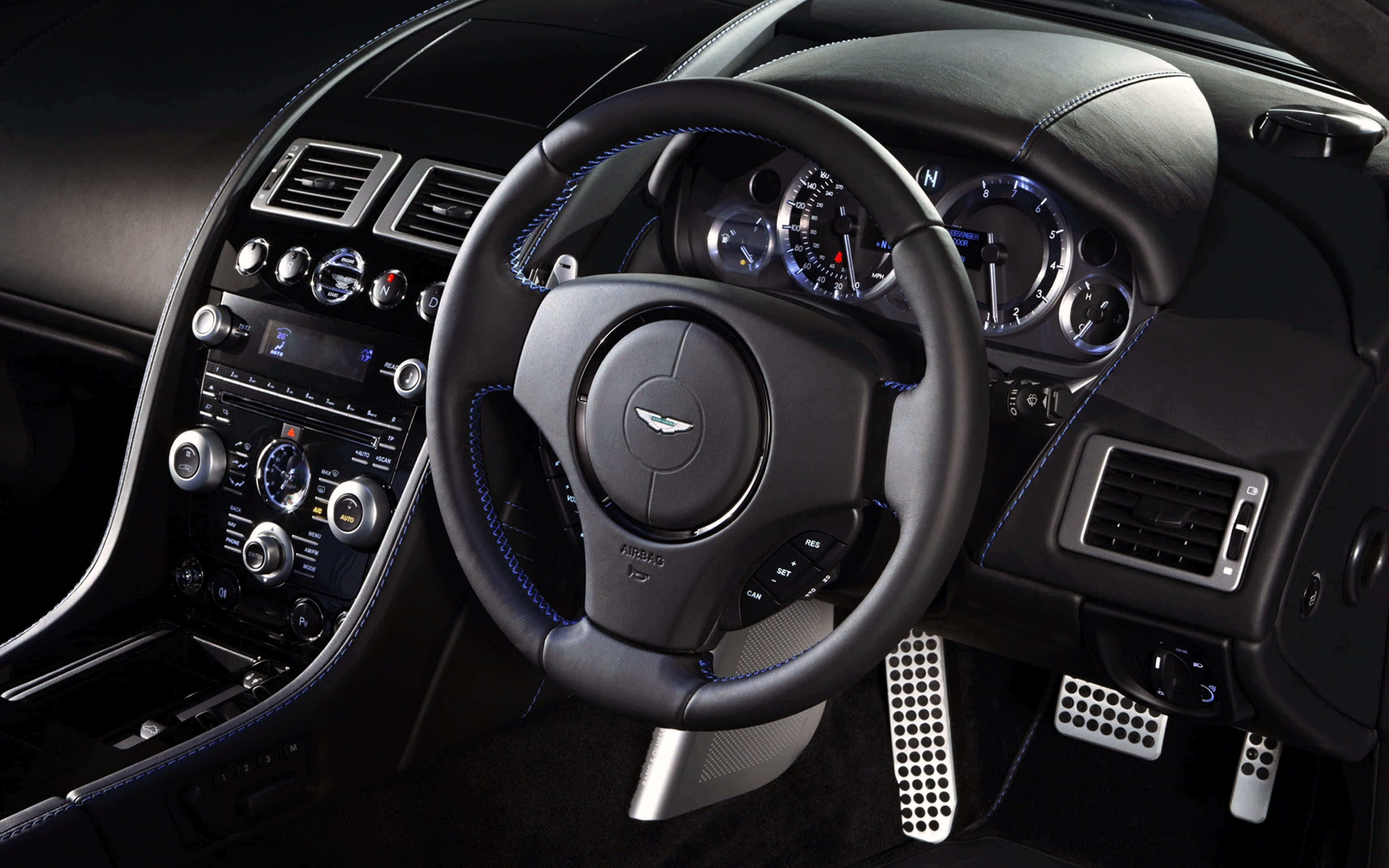 Steering Wheel 桌布 壁紙 — 豪華車內裝，配備黑色皮革方向盤、藍色縫線和發光儀表組。