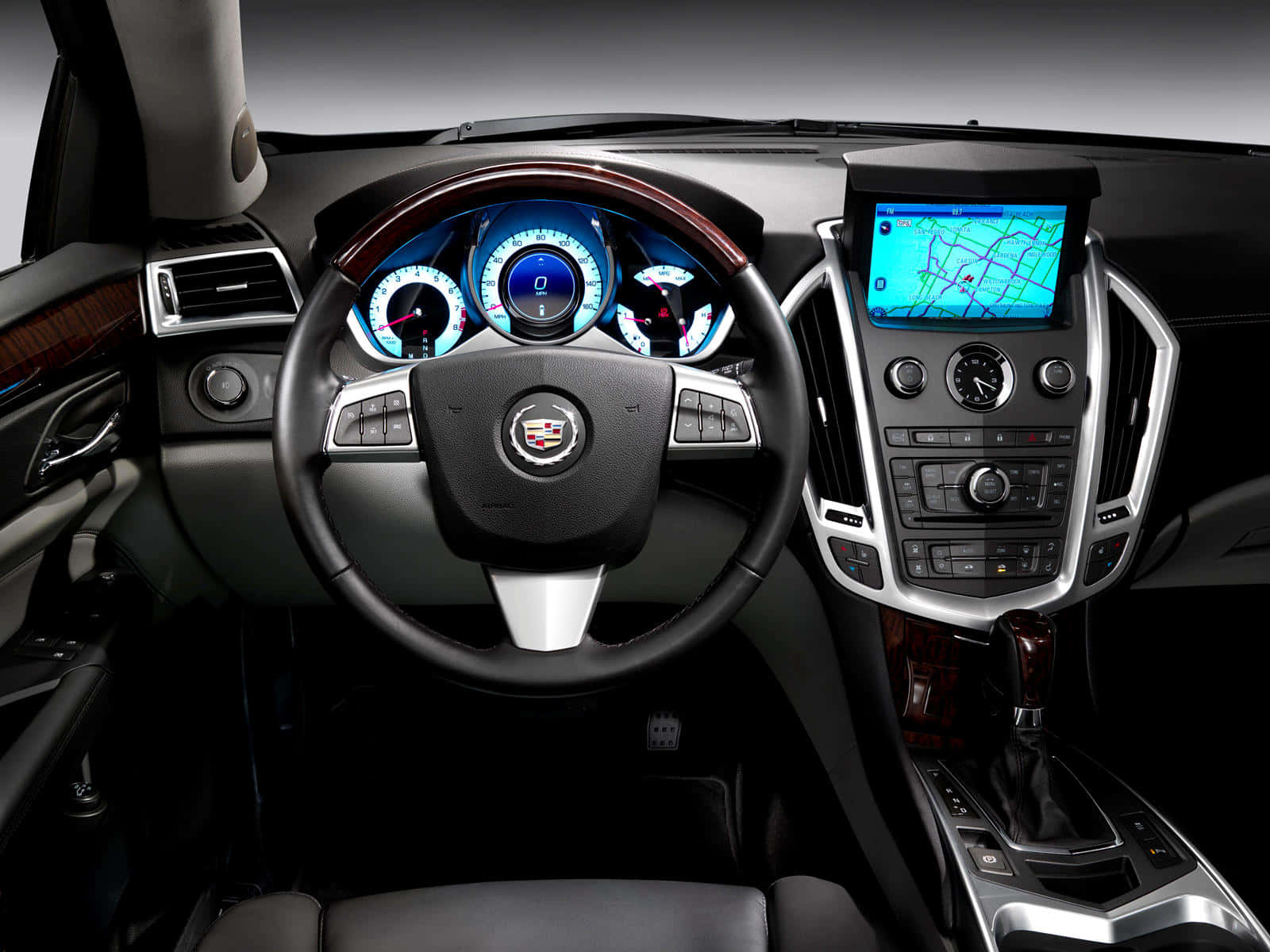 Cadillac Srx 桌布 壁紙 — 豪華車內裝，配有發光藍色儀表板與木質飾邊，在攝影棚燈光下。
