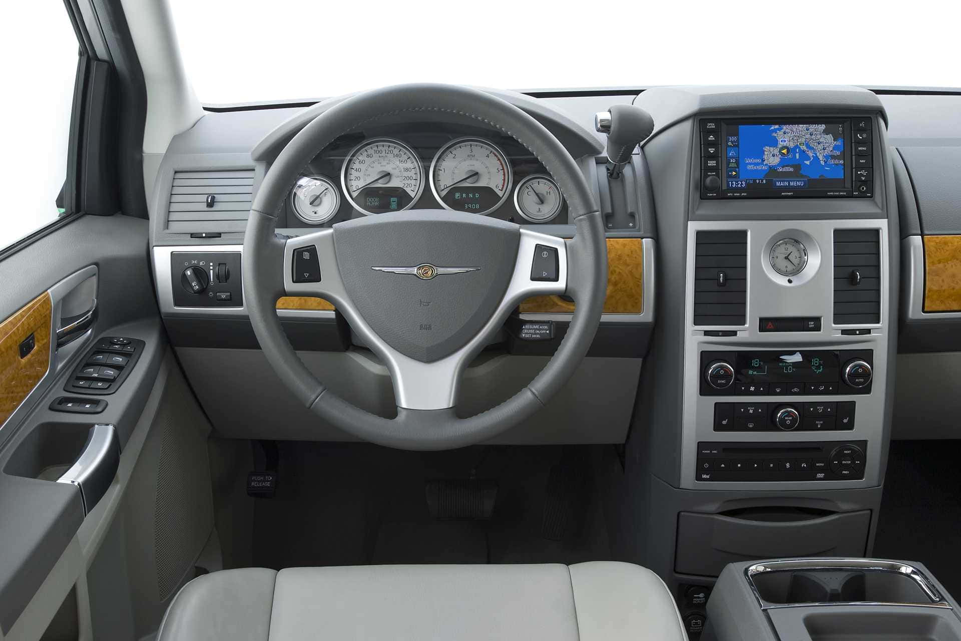 Chrysler Voyager 桌布 壁紙 — 豪華車內裝，灰色皮革座椅，木質飾邊和數位導航螢幕。