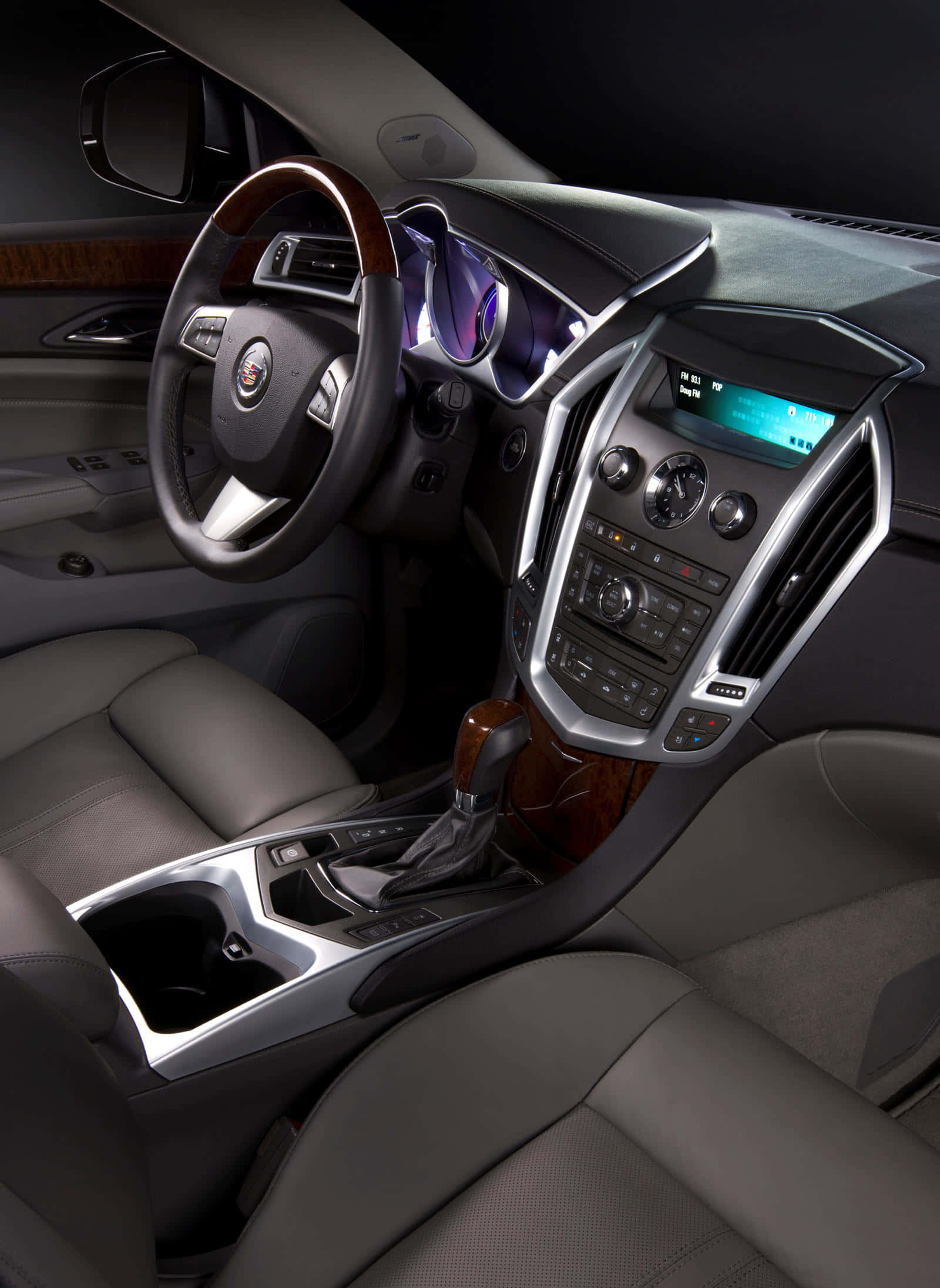 Cadillac Srx 桌布 壁紙 — 豪華車內裝，配備皮革座椅、木飾邊和發光數位顯示螢幕，在昏暗的環境燈光下。