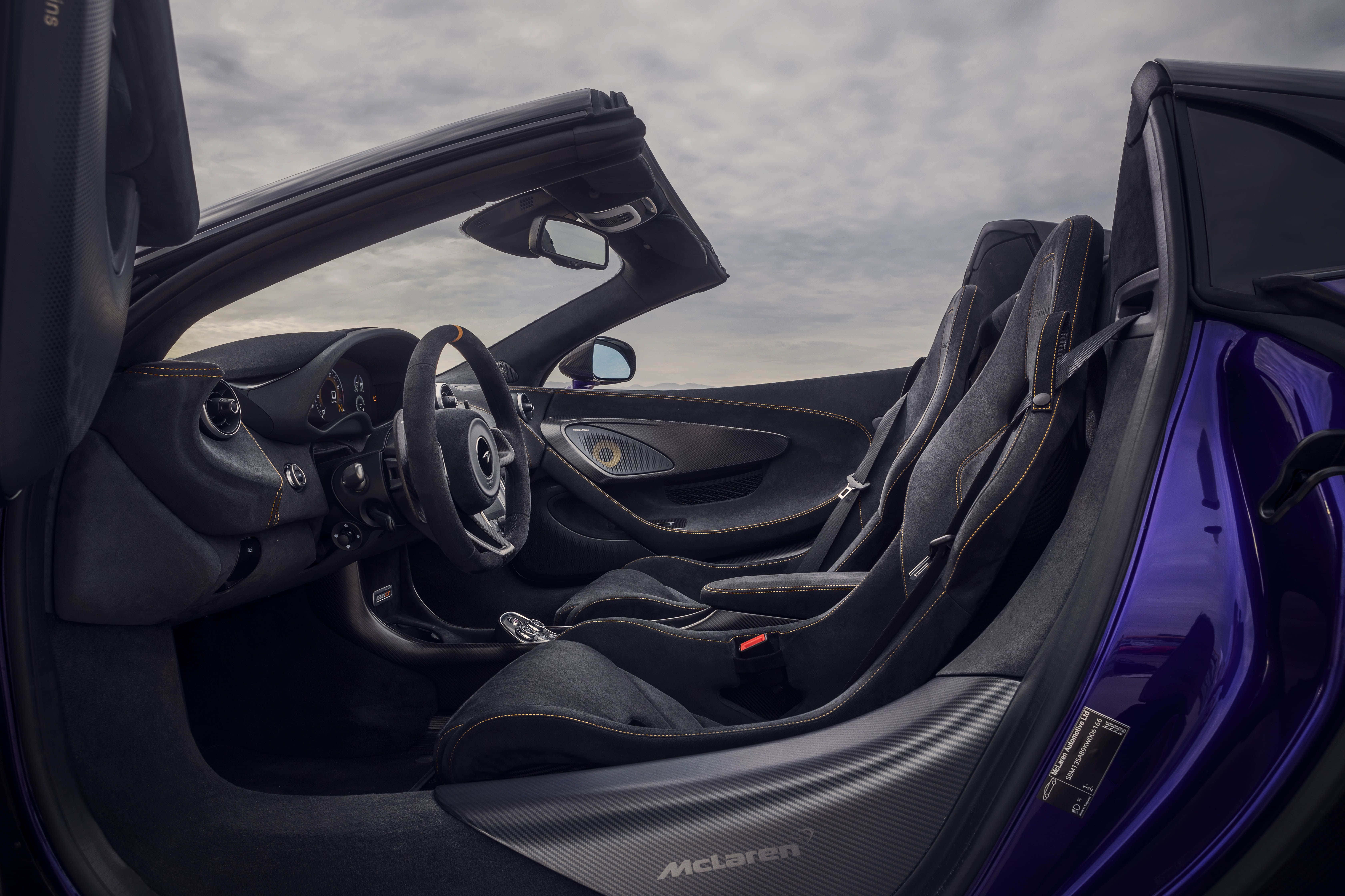 Mclaren 600lt Spider 桌布 壁紙 — 豪華跑車內裝，配備黑色皮革座椅和碳纖維飾邊，天空多雲。
