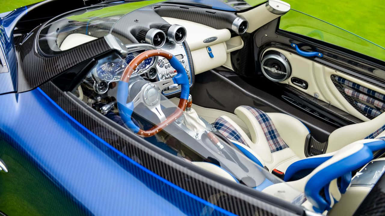 Pagani Zonda Hp Barchetta 桌布 壁紙 — 豪華跑車內飾，配備藍色碳纖維飾邊、奶油色皮革座椅和木質方向盤，背景為綠色草地。