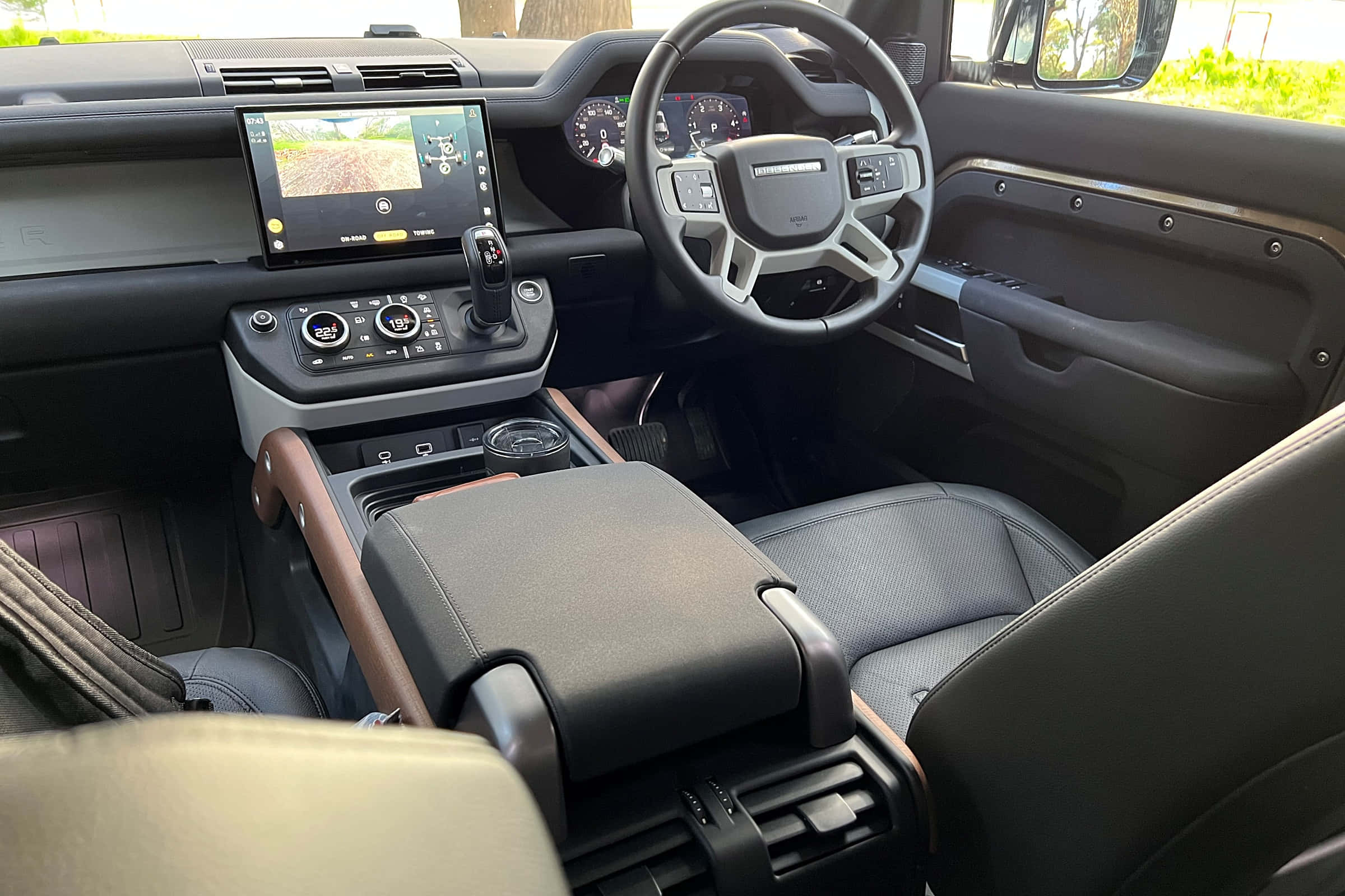 Land Rover Defender 桌布 壁紙 — 豪華SUV內裝，配備黑色真皮座椅、木質飾邊和顯示越野地形的數位儀表板。