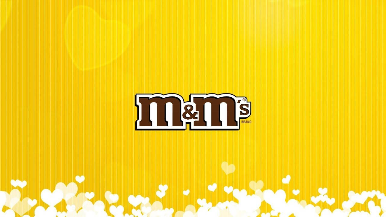 Chocolate 桌布 壁紙 — M&M's 標誌居中於充滿活力的黃色條紋背景上，底部有白色心形散景。