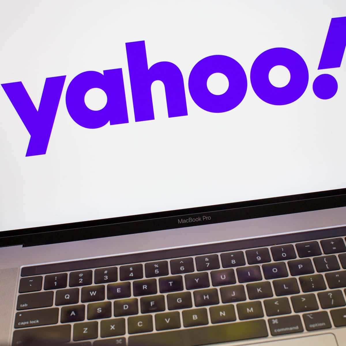 Yahoo 桌布 壁紙 — MacBook Pro 的特寫，在明亮的白色螢幕上顯示大膽的紫色 Yahoo 標誌。