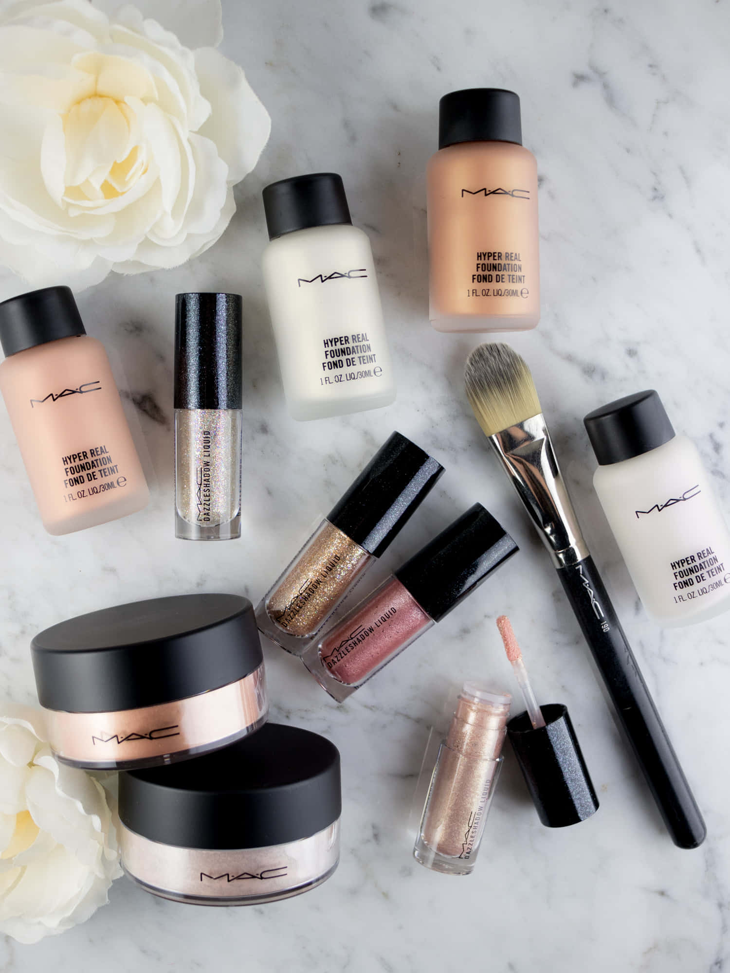 Mac Cosmetics 桌布 壁紙 — MAC化妝品排列在大理石上，搭配白玫瑰，營造出奢華的美容產品展示。