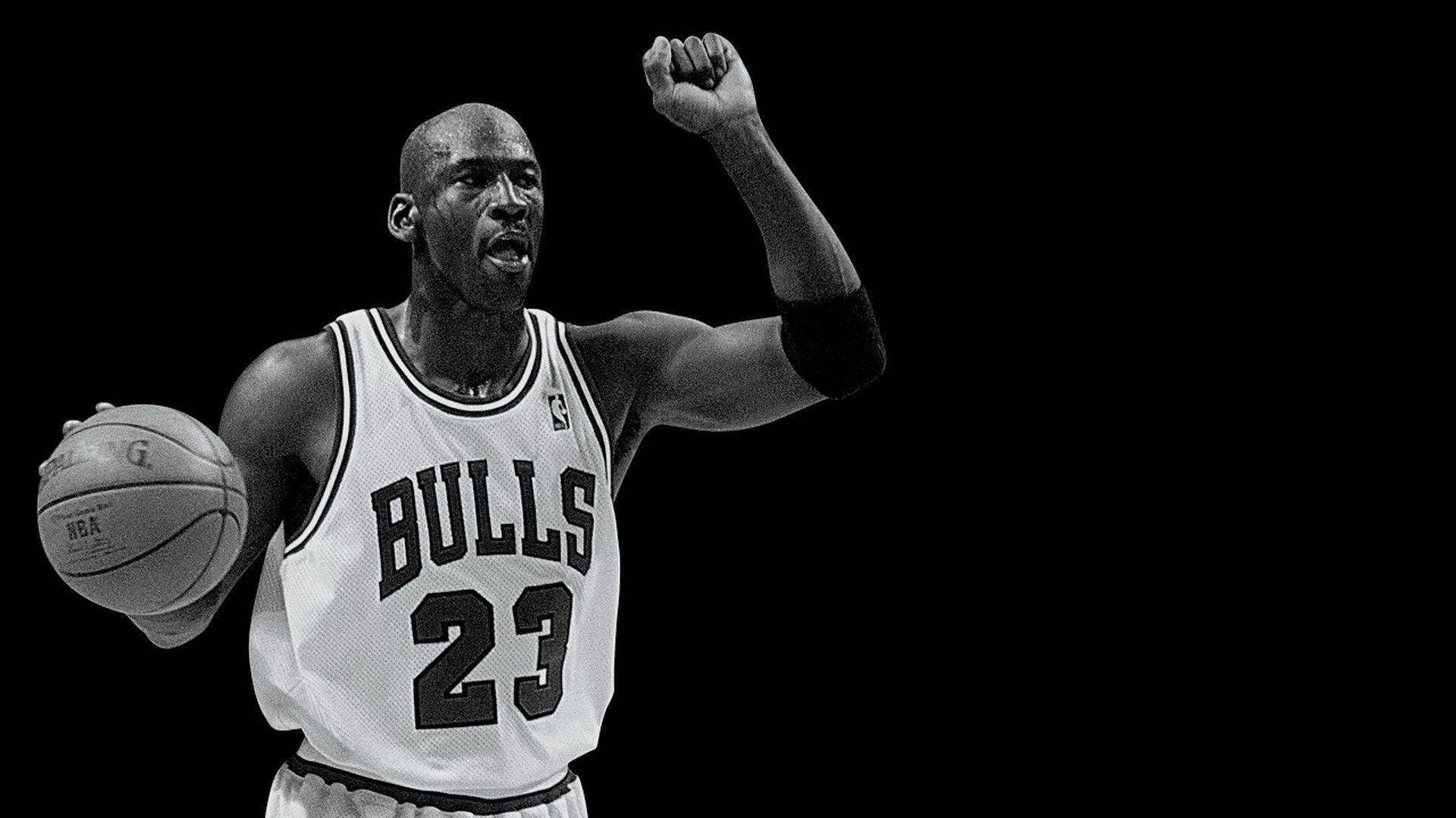 麥可喬丹身穿公牛隊球衣，手持籃球慶祝勝利。 — Jordan Logo 壁紙