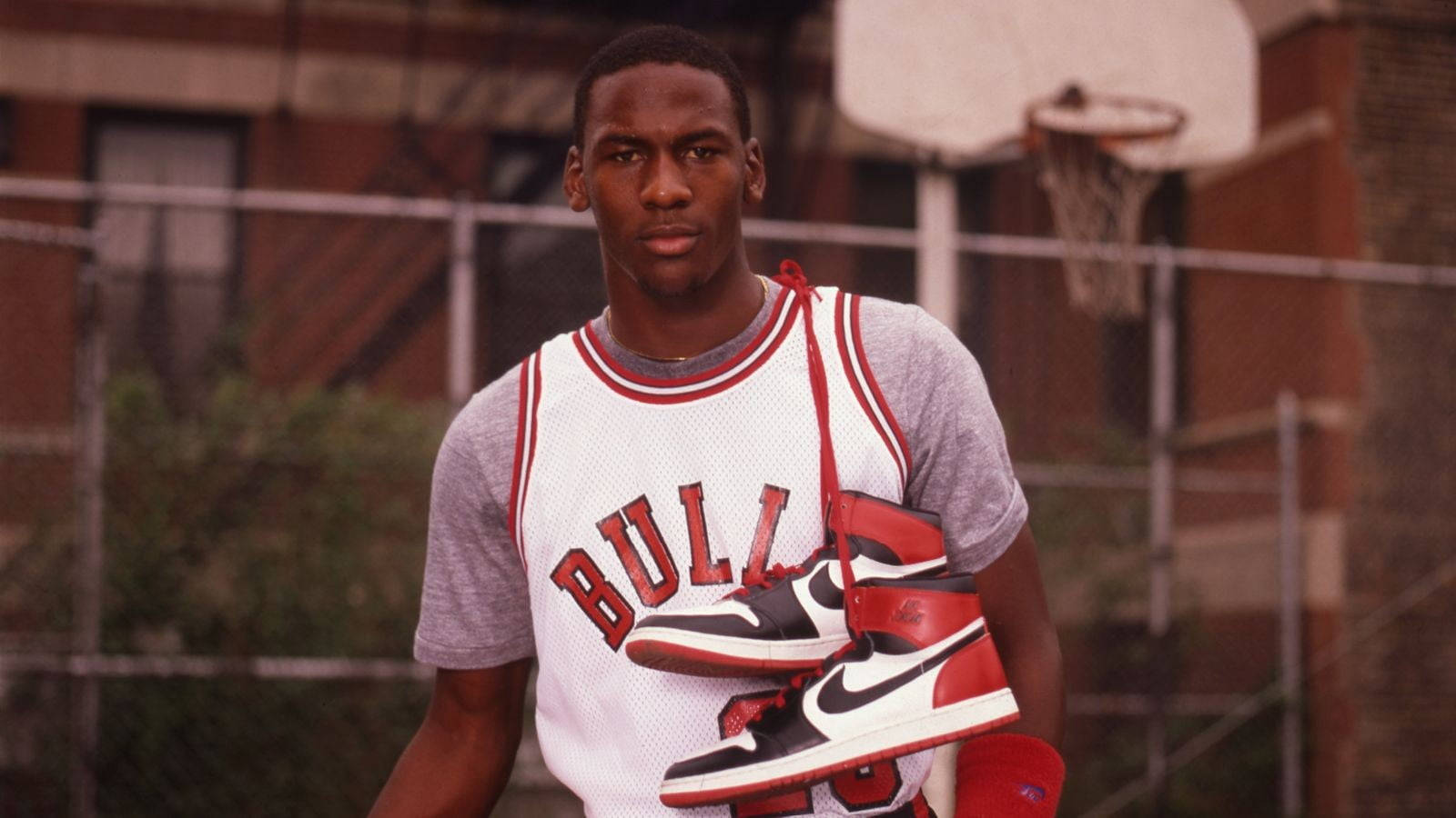 麥可喬丹在籃球場上拿著 Air Jordan 1 運動鞋。 — Jordan Logo 壁紙