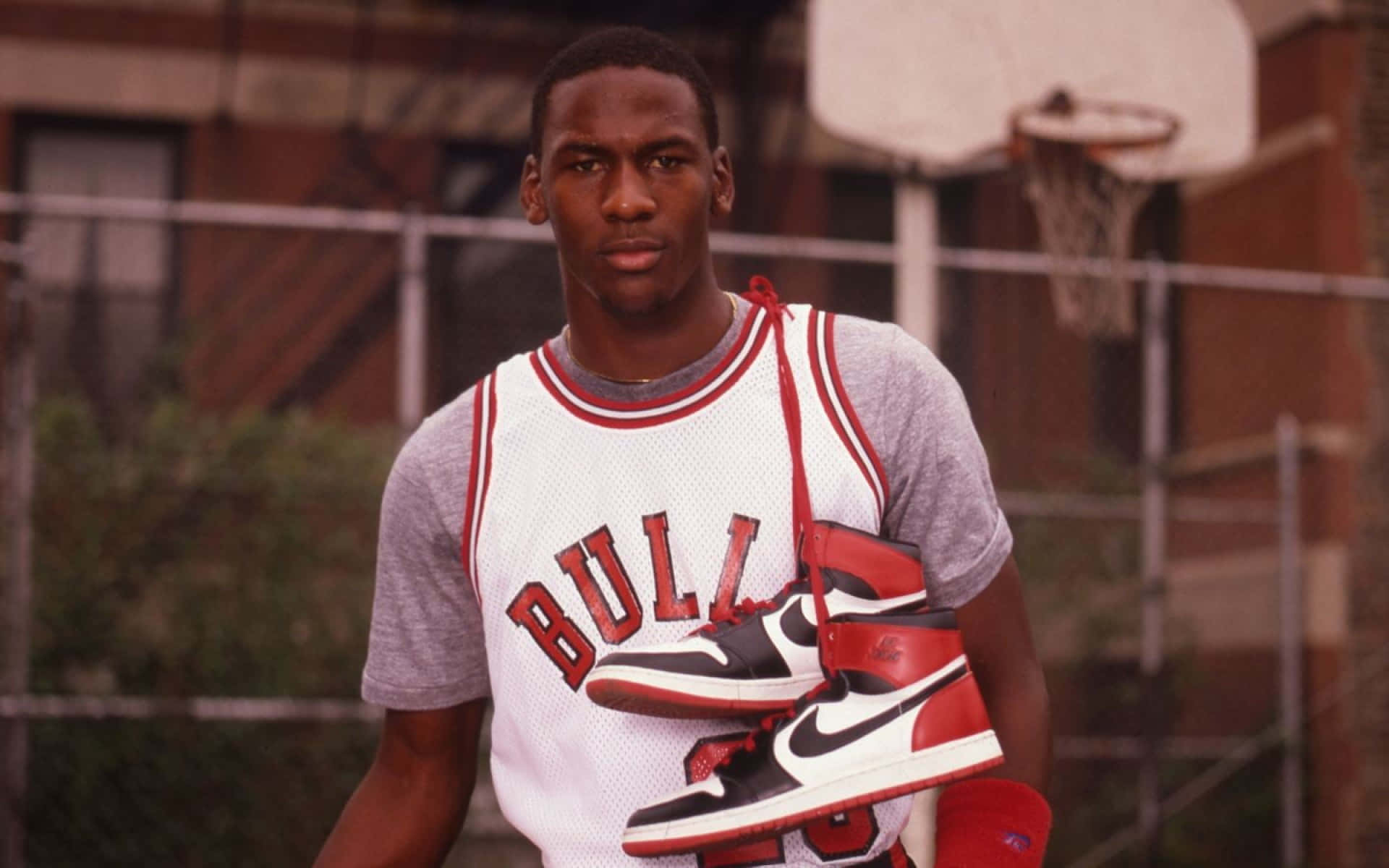 麥可喬丹在籃球場上拿著Air Jordan 1運動鞋。 — Jordan Logo 壁紙