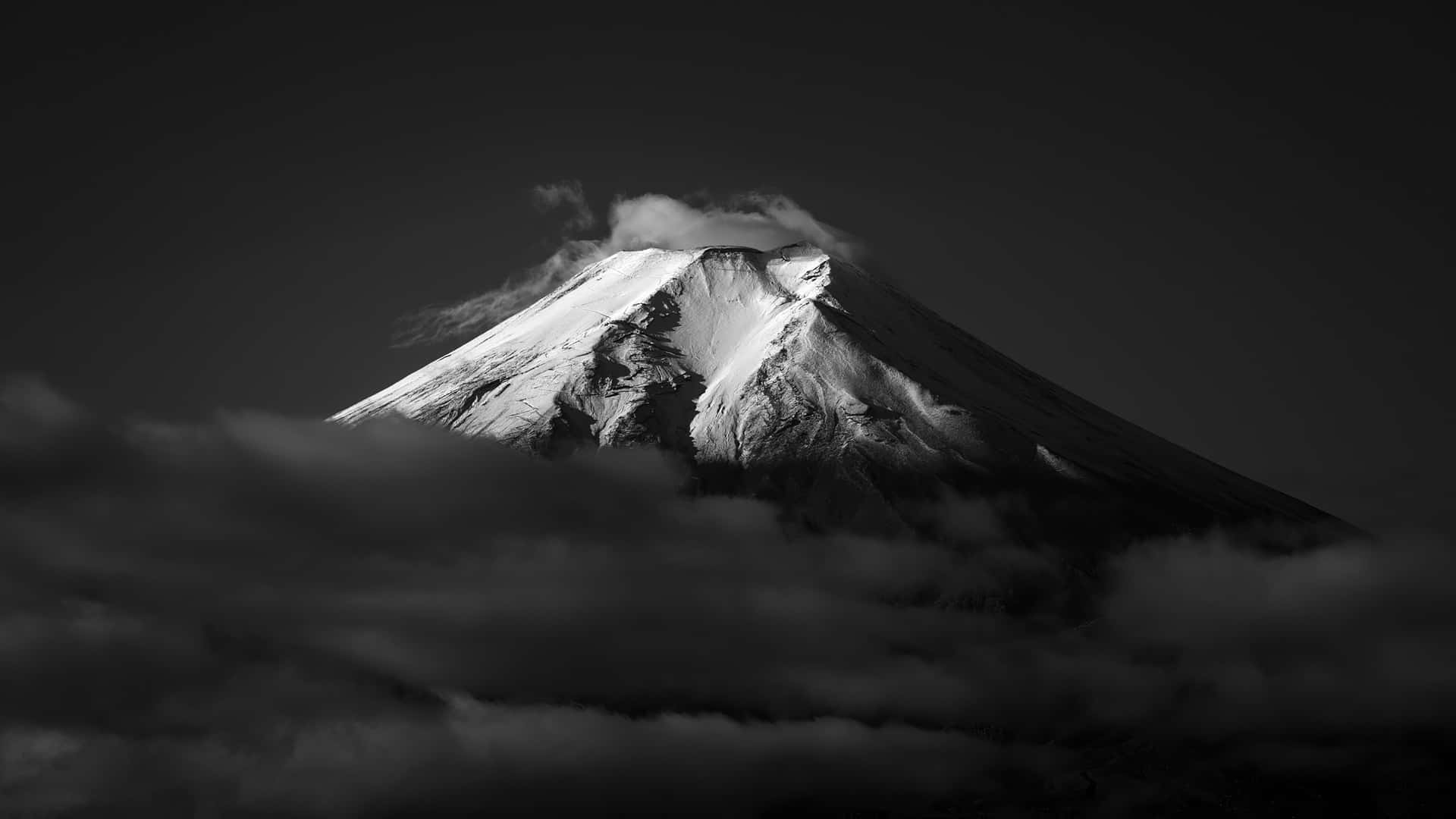 白雪覆蓋的山峰從黑白相間的烏雲中浮現。 — 富士山 壁紙
