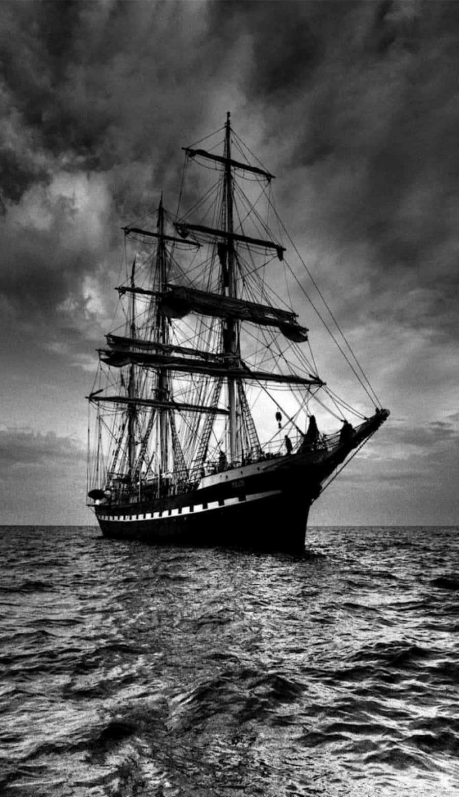 Black And White Storm 桌布 壁紙 — 一艘雄偉的高桅帆船在波濤洶湧的海面上航行，天空烏雲密佈，呈現鮮明的黑白效果。